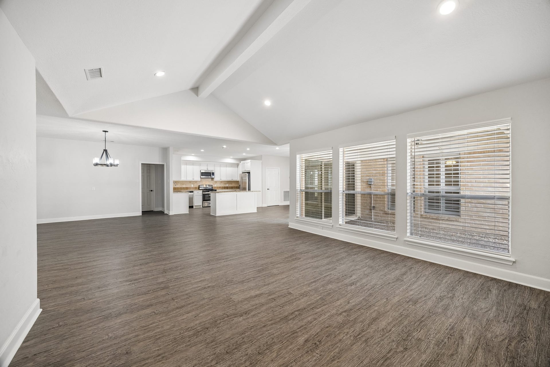 View of the open concept from the family room. On the left is the formail dining area, with access to utility and garage through the doorway. Open kitchen and breakfast area to the right.