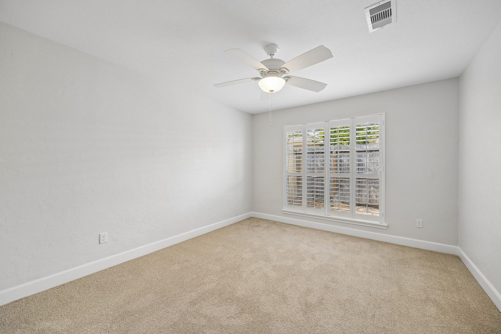 Secondary bedroom with carpet, plantation shutters, and a lighted ceiling; this room shares access to the hall bath.