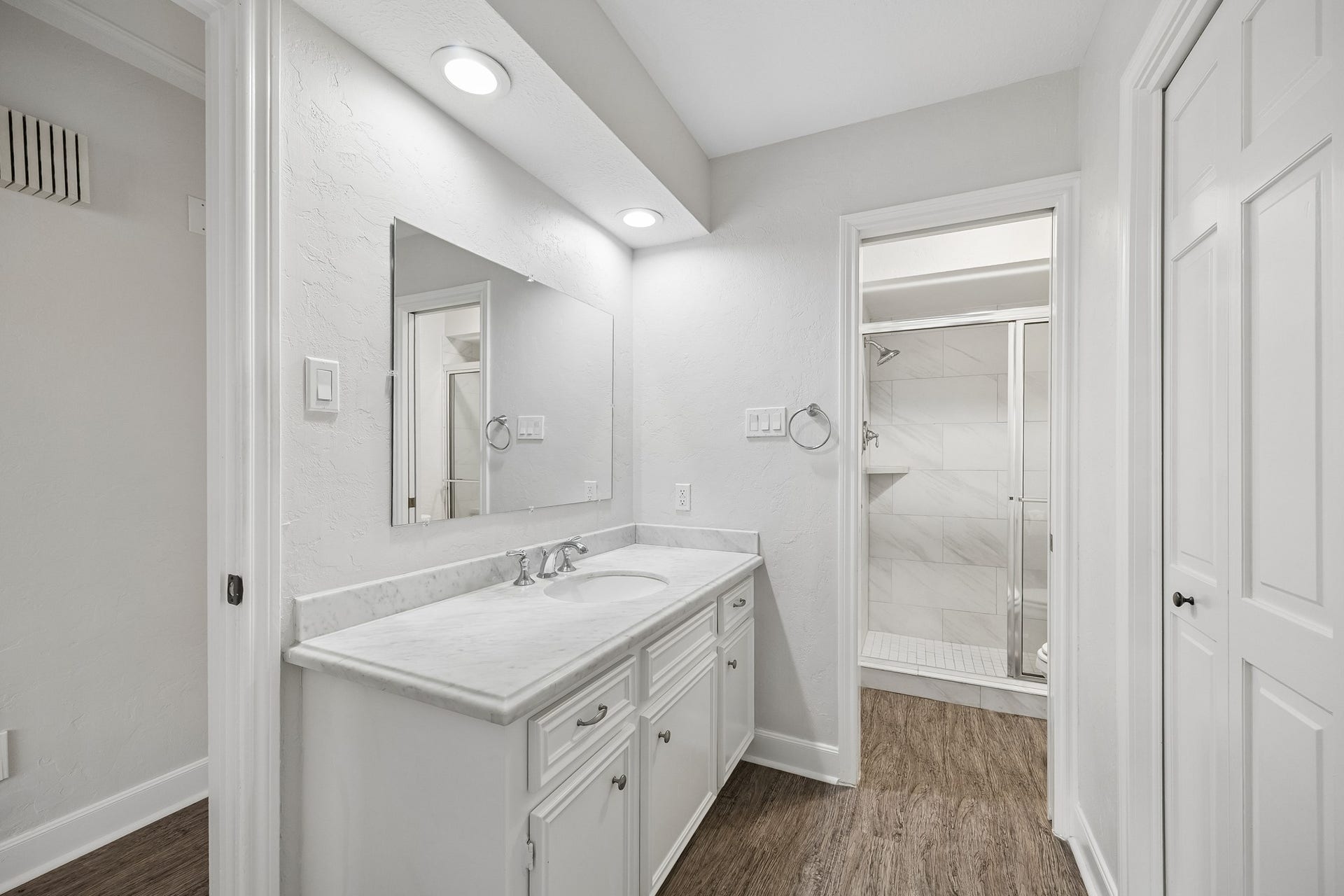 Secondary bathroom with walk-in shower, cultured marble counters, and storage closet.