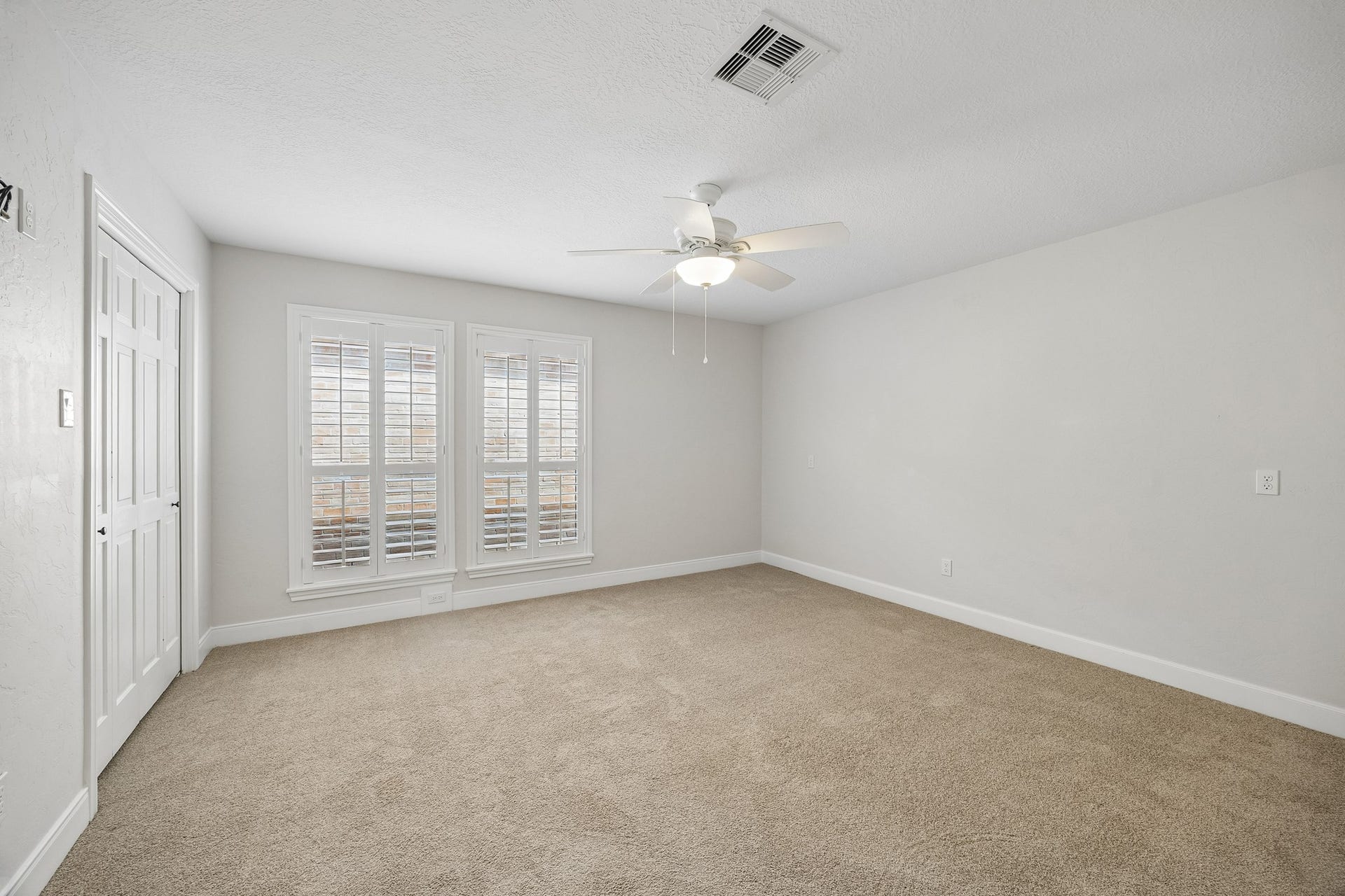 Secondary bedroom off front entry, with carpet, dual closets, and plantation shutters.