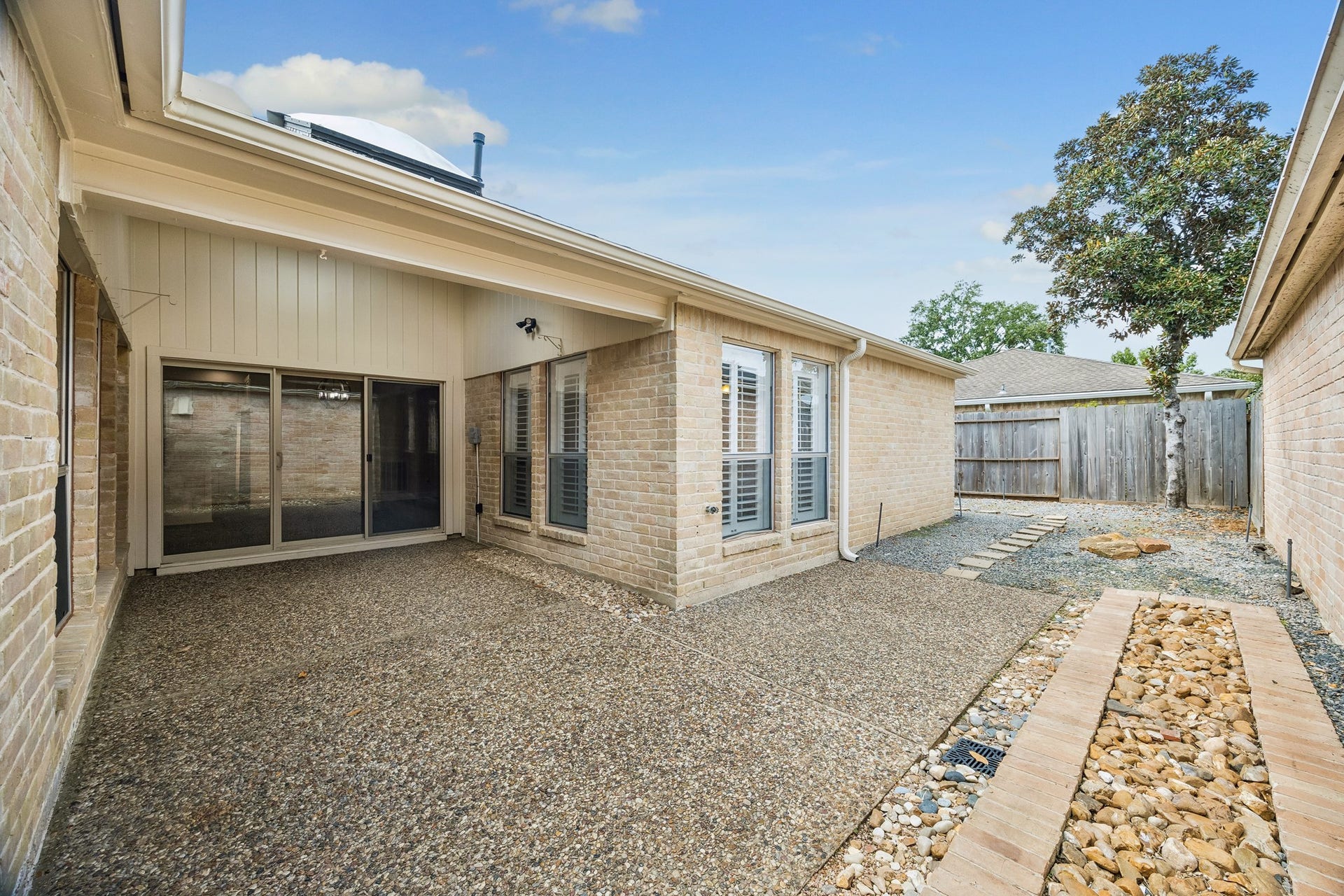 View of the covered patio and back area of the home. Note the low-maintenance landscaping.