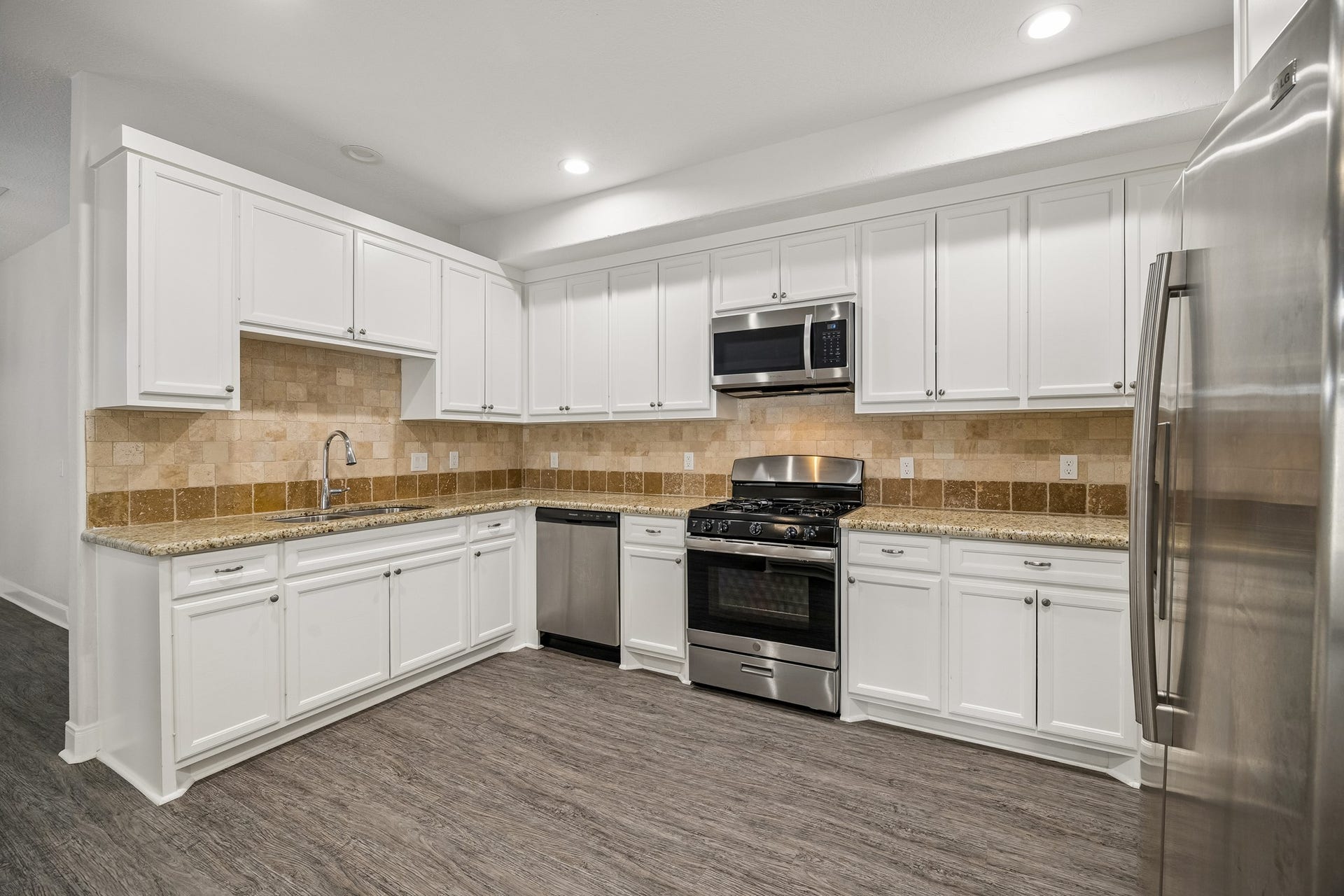 Spacious kitchen with granite counters, gas oven and range, stainless steel dishwasher, and refrigerator to stay with the home.