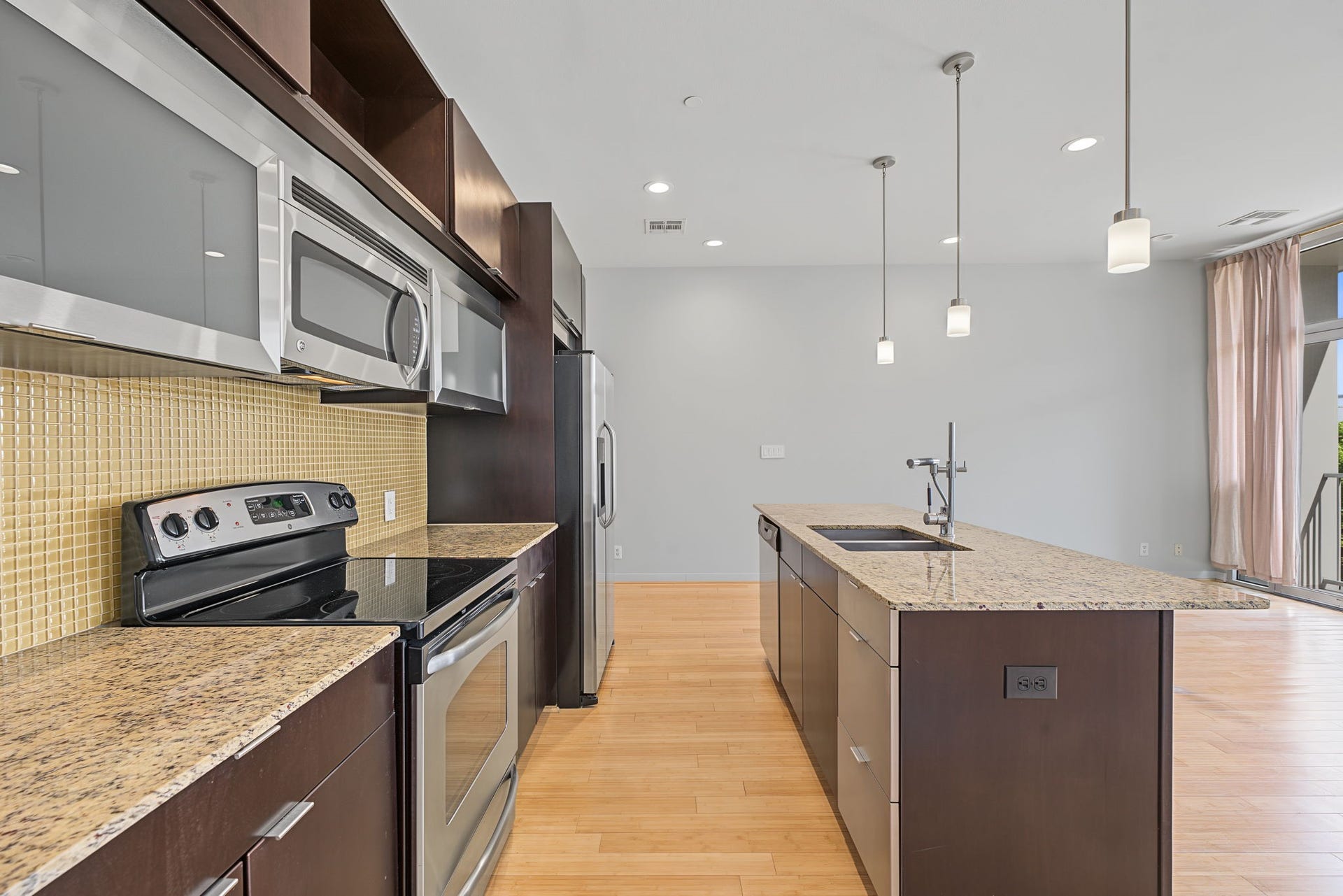 Modern design takes center stage in this stylish kitchen! Frosted glass-front cabinetry adds a sophisticated European flair, beautifully complemented by gleaming stainless steel appliances, including an electric range/oven, microwave, dishwasher, and refrigerator/freezer.