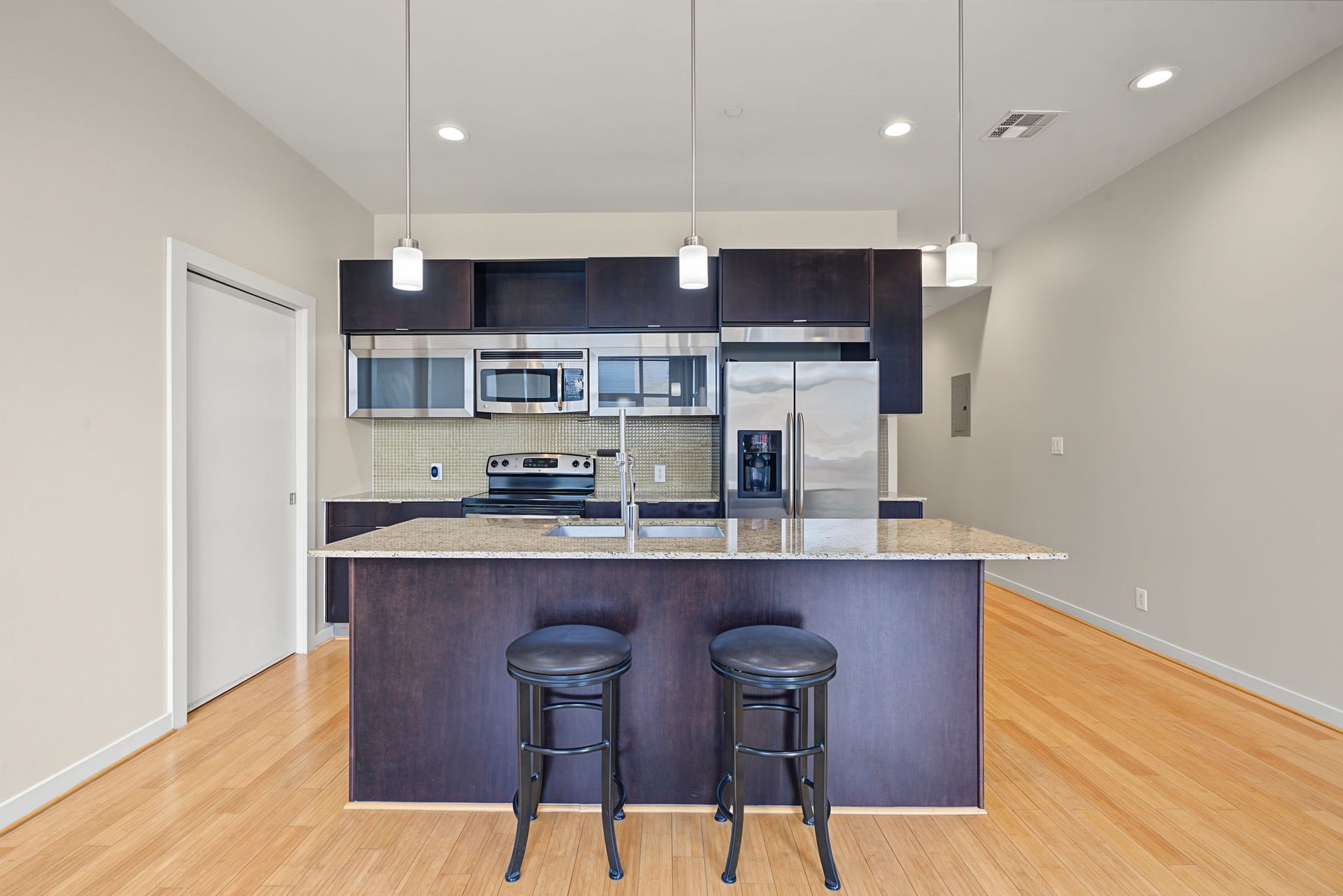 Beautiful granite countertops take center stage in this stylish kitchen, complemented by a crisp mosaic tile backsplash that adds texture and visual interest. Sleek pendant lighting provides a warm glow, bringing depth and dimension to this contemporary space!