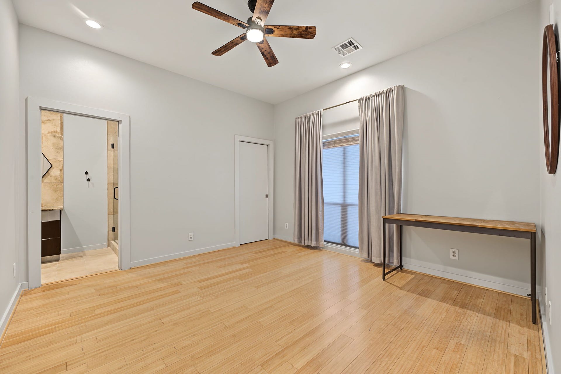 A spacious walk-in closet with sunny window provides plenty of room for wardrobe storage, while a sleek pocket door leads to the private en-suite bath, maximizing usable space while maintaining the home's clean, contemporary aesthetic.