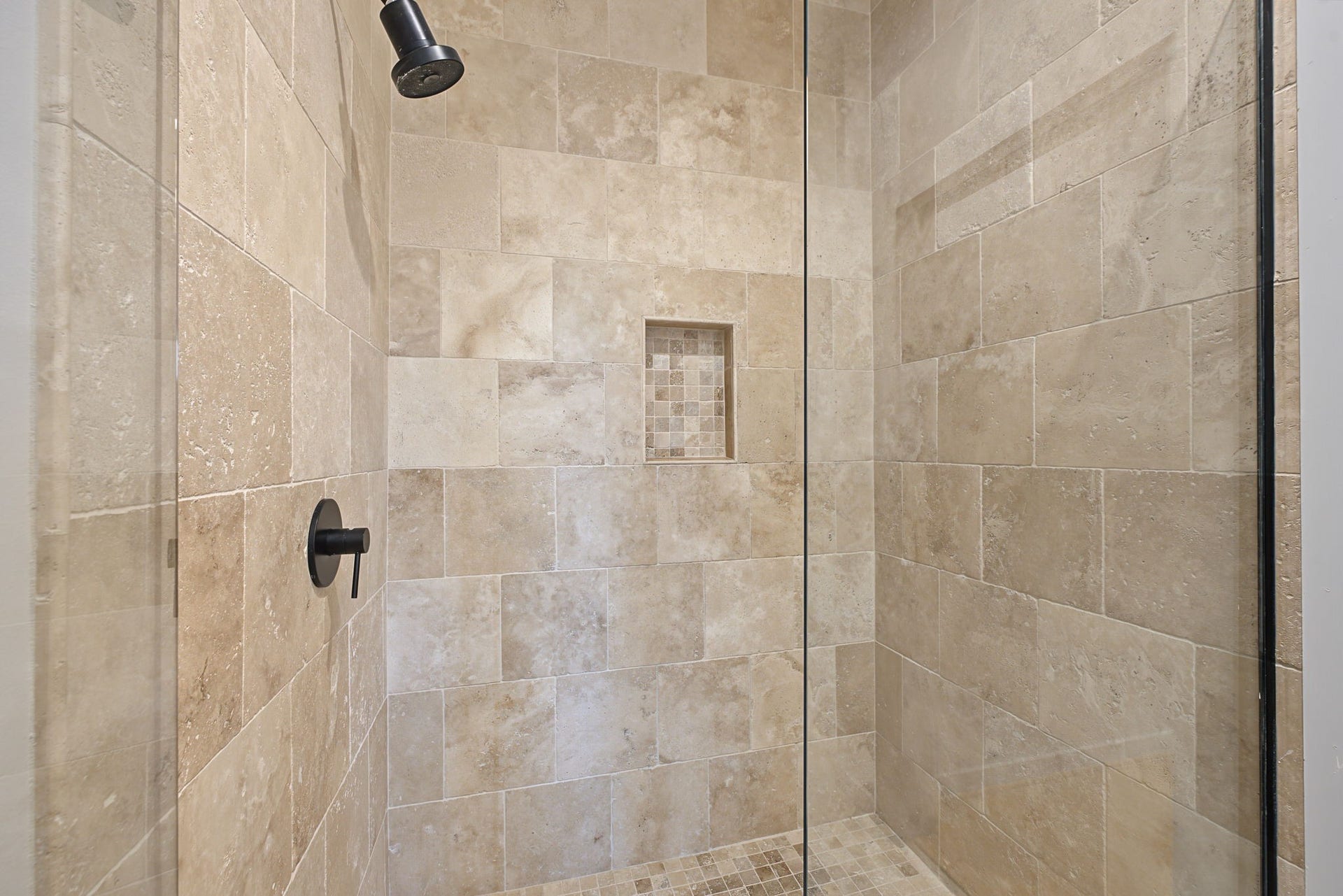 Spa-Inspired Comfort! The spacious walk-in shower showcases beautiful travertine tile, a sleek glass enclosure, and a recessed toiletry niche that keeps bathing essentials conveniently within reach. Its clean lines and natural stone finishes create a relaxing atmosphere with timeless contemporary appeal!