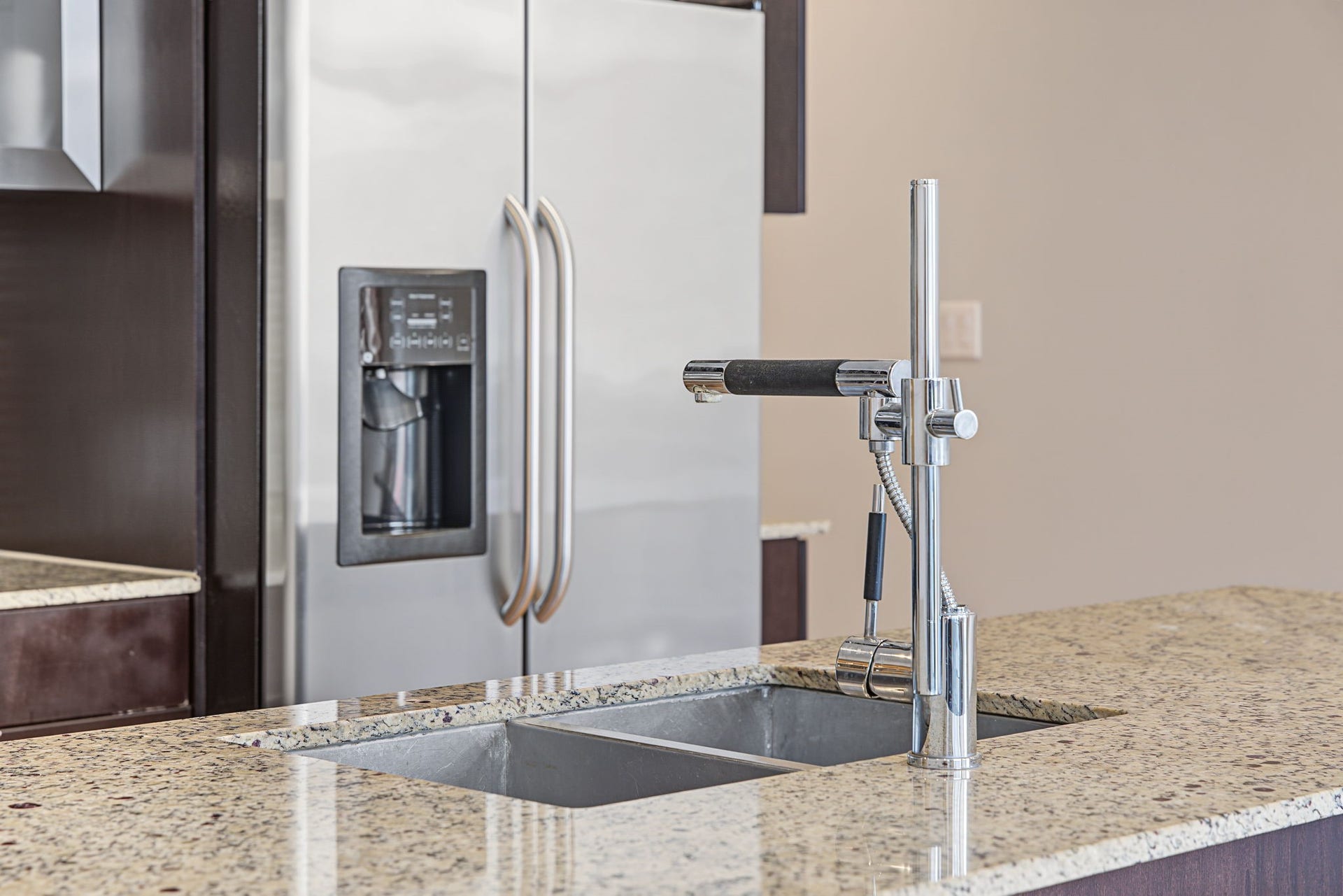 A striking, commercial-inspired chrome faucet with a convenient pull-out spray wand adds a distinctive designer touch to the kitchen. Paired with a double stainless steel sink and beautiful granite countertops, this sleek fixture combines modern sophistication with practical convenience for meal preparation and cleanup!