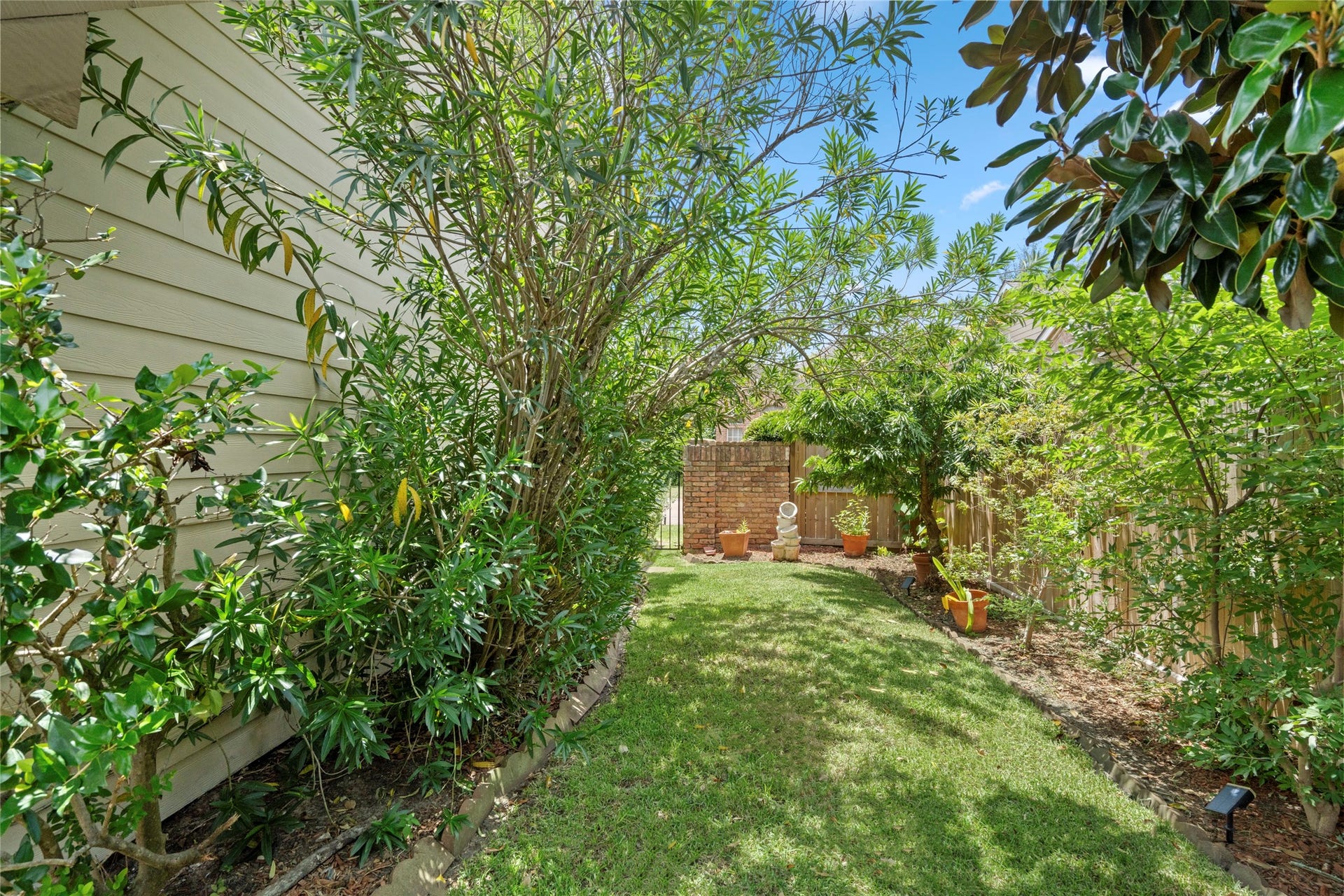 A view of the backyard garden area, highlighting the mature trees and greenery that create a serene outdoor escape.