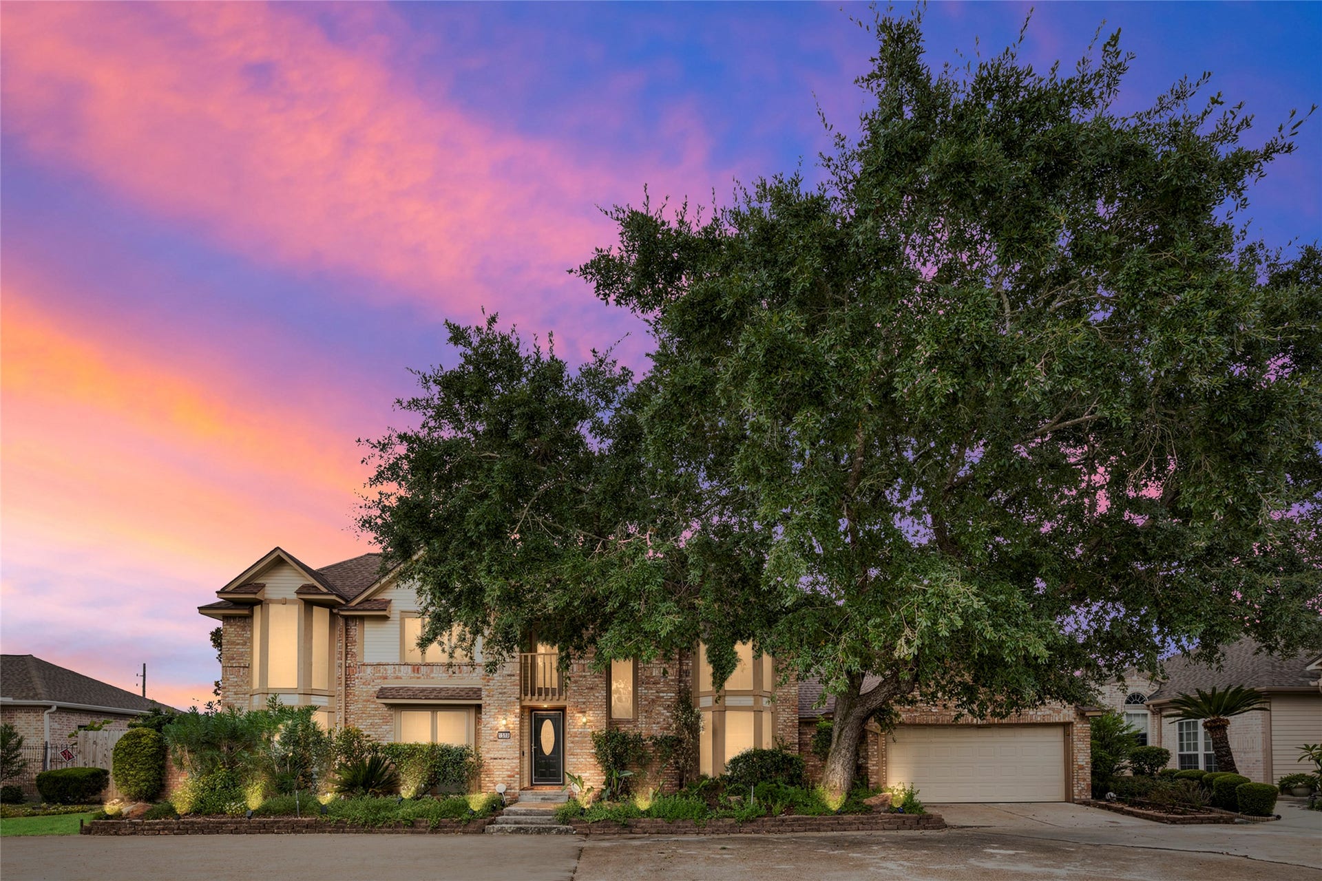 A stunning twilight exterior shot capturing the home bathed in sunset sky, showcasing its curb appeal and commanding presence on the lot as dusk falls.