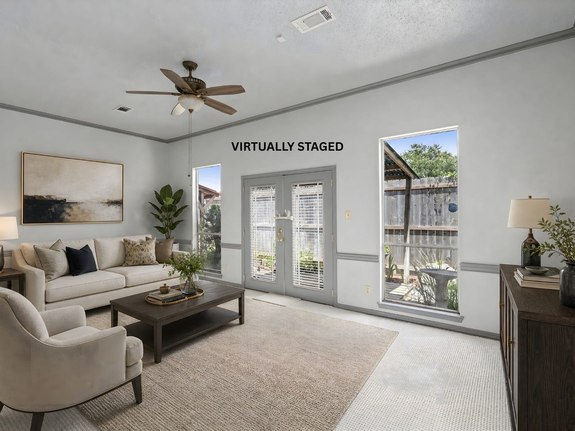A virtually staged living room view with French doors, showing how natural light and a comfortable seating arrangement make this an inviting retreat.