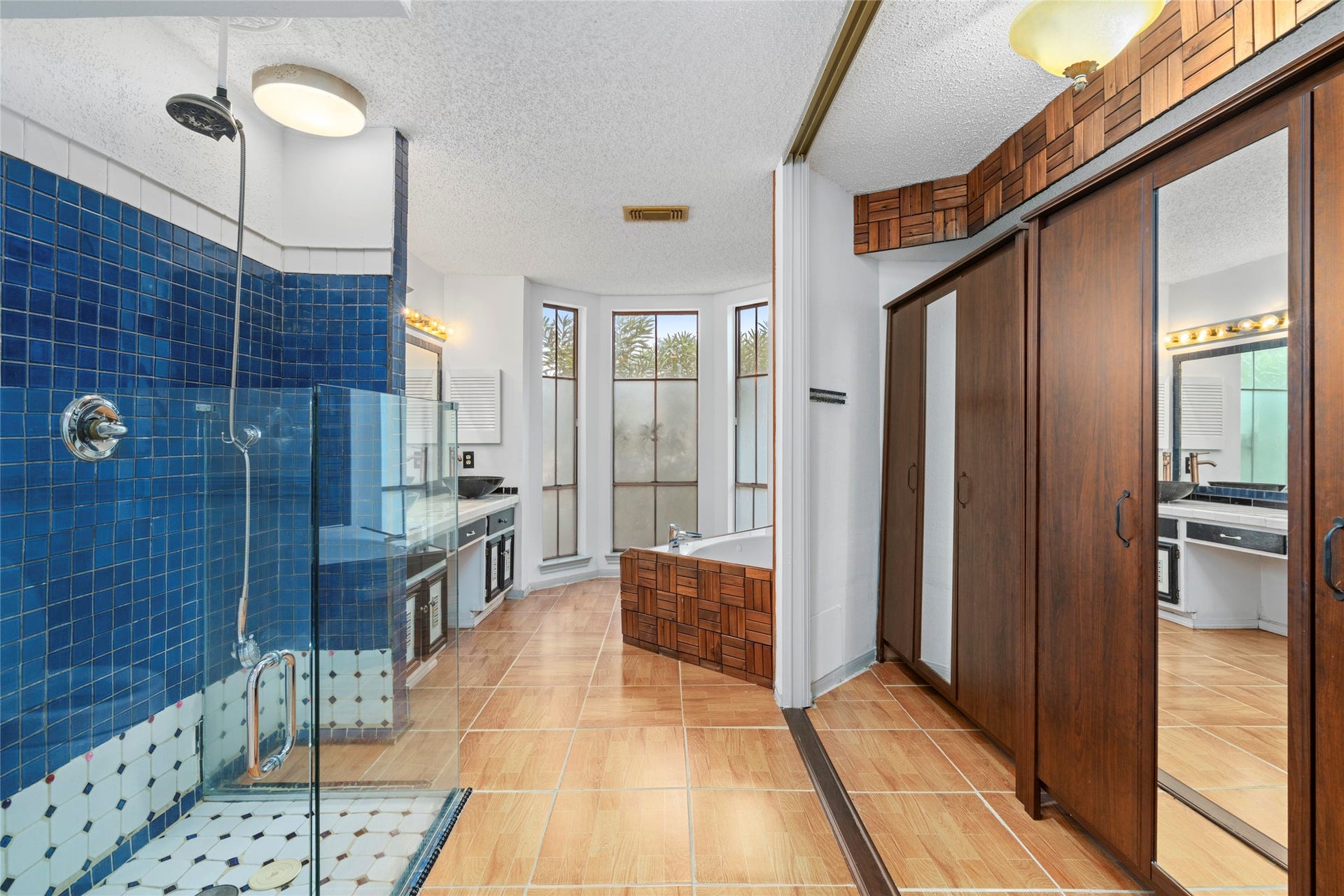 A connecting bathroom/closet area with matching blue tile and a rich wood door, showing thoughtful design details throughout.