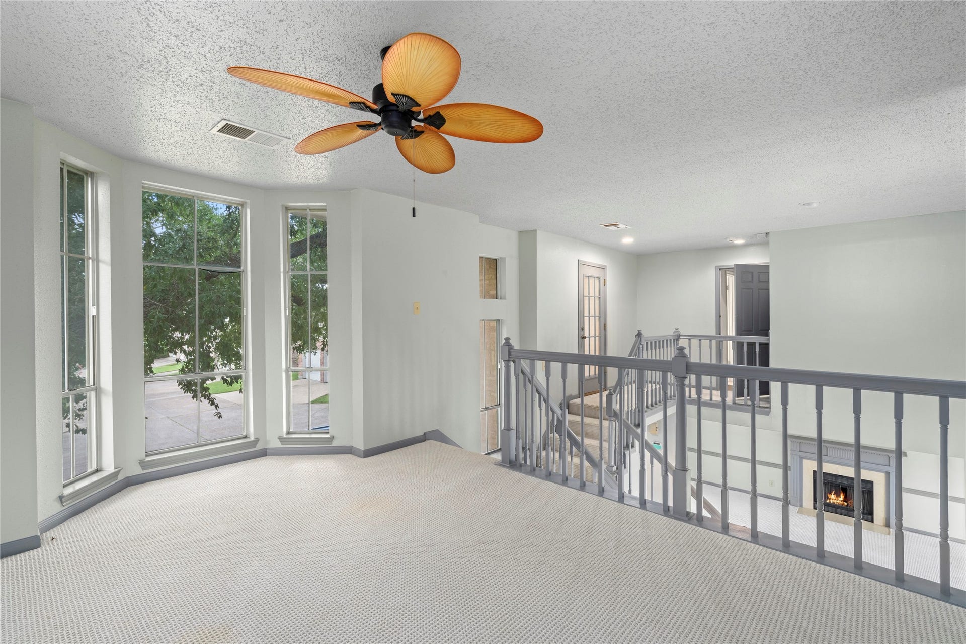 An open loft-style room overlooking the staircase railing below, offering a versatile flex space with a great view of the home's interior.