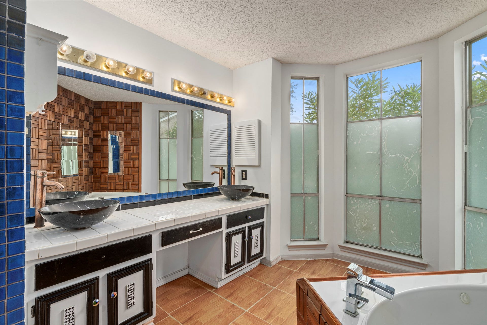 A bathroom vanity with a large mirror and windows, offering bright, functional space to start the day.