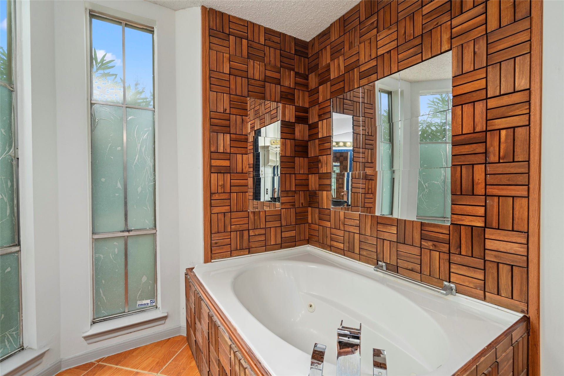A bathroom featuring a wood-toned tiled tub surround, adding warmth and a distinctive design element to this en-suite.