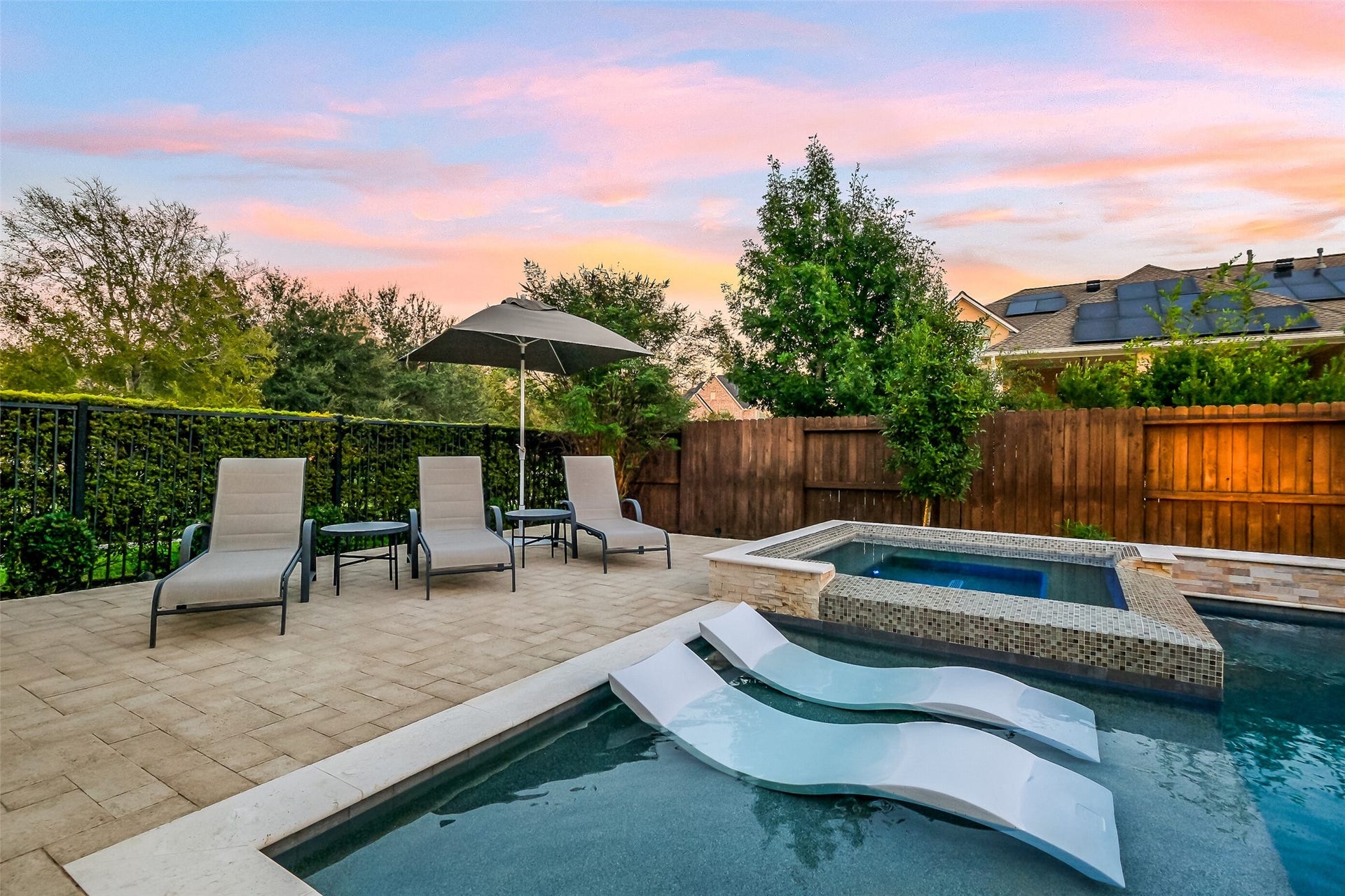 This close up of the pool's tanning ledge and elevated spa showcase the quality of craftsmanship of this outdoor area. Youll love the extra patio space for entertaining and the multiple entertainment areas featured in this back yard. Ledge Loungers can stay with the pool!