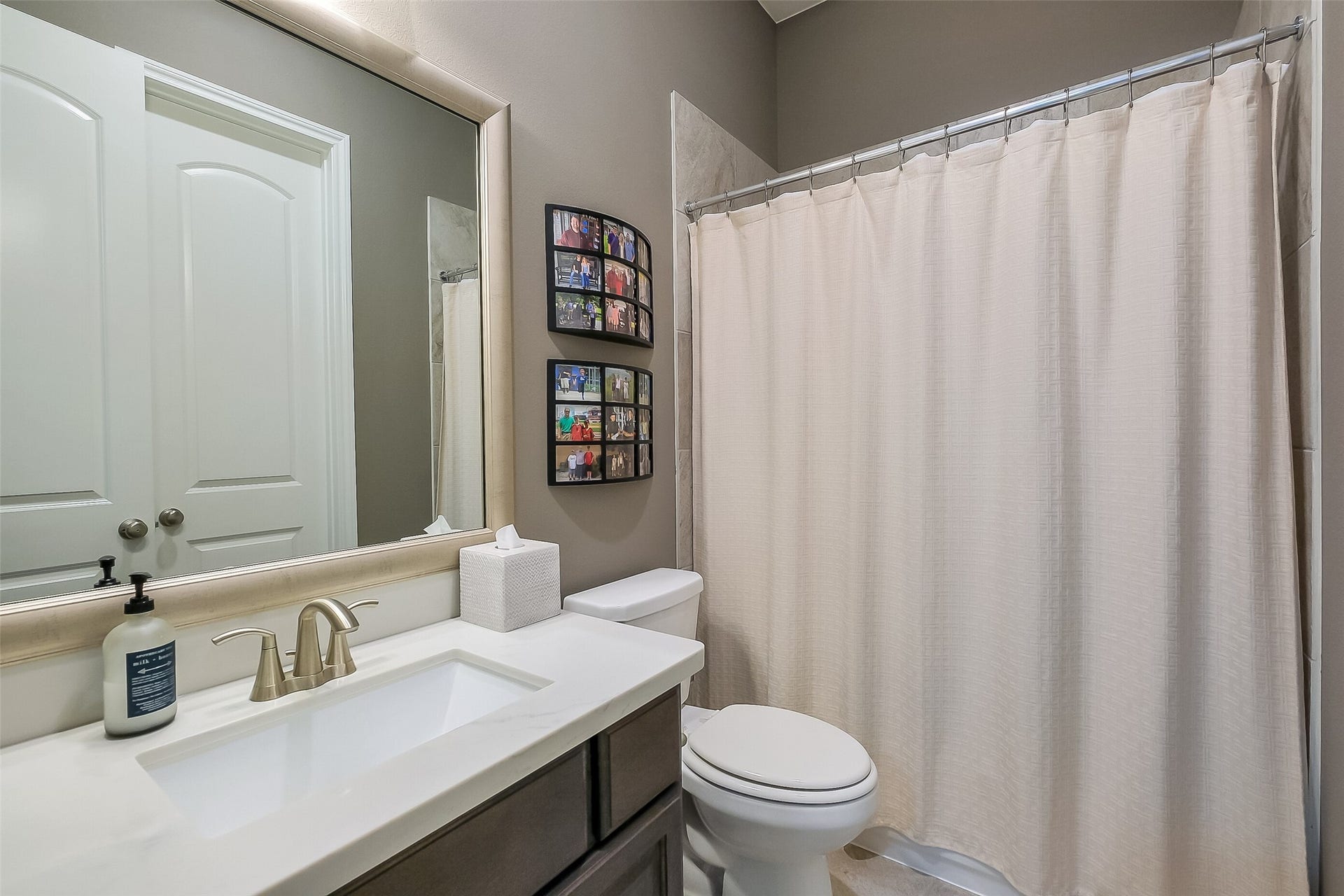 This secondary first floor full bathroom offers a quartz-topped vanity, brushed nickel fixtures, and a tiled tub/shower  a clean, comfortable space for guests or family.