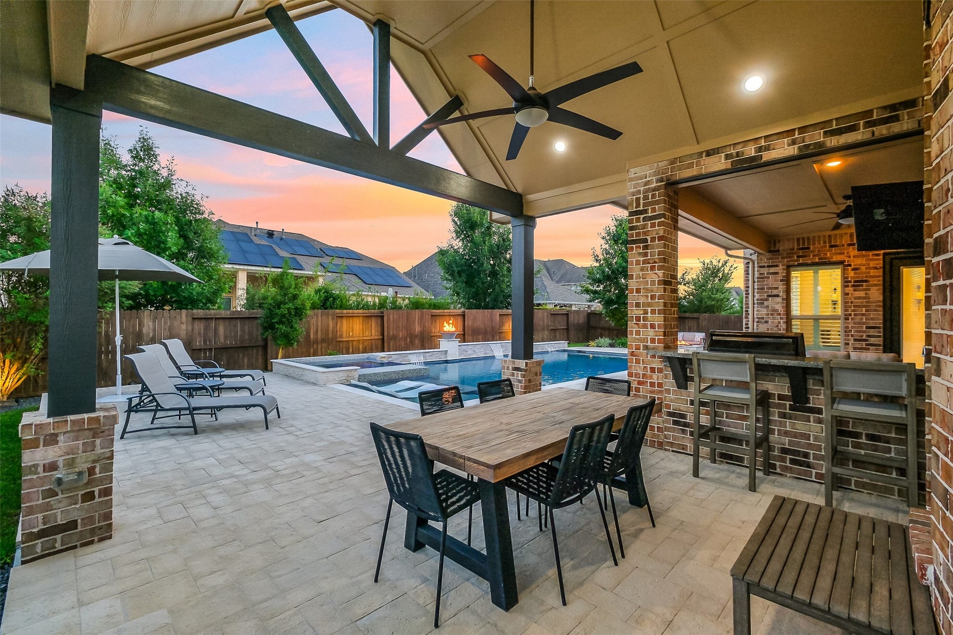 As the sun sets, this extended covered outdoor dining and kitchen area truly comes alive  complete with a ceiling fan, surround sound, outdoor grill, and bar seating overlooking the pool. It's an entertainer's go-to spot for Texas evenings.