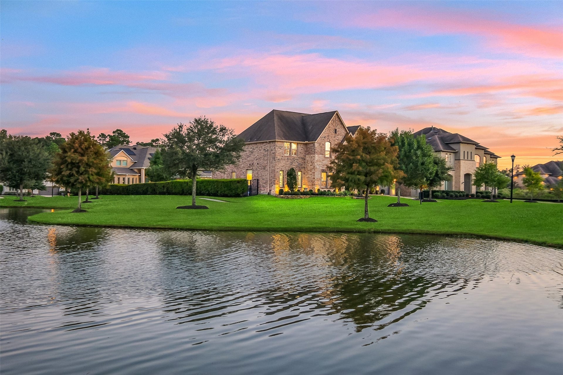 As twilight settles in, this home's brick and stone exterior glows warmly against the backdrop of the neighborhood pond  a reminder of just how private and picturesque this setting truly is.