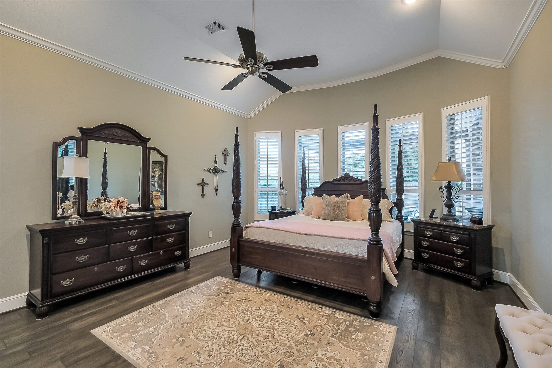 This primary suite offers a warm but spacious retreat with its vaulted ceiling, upgraded paint and rich wood floors. Plantation shutters frame the windows, filling the room with soft natural light.