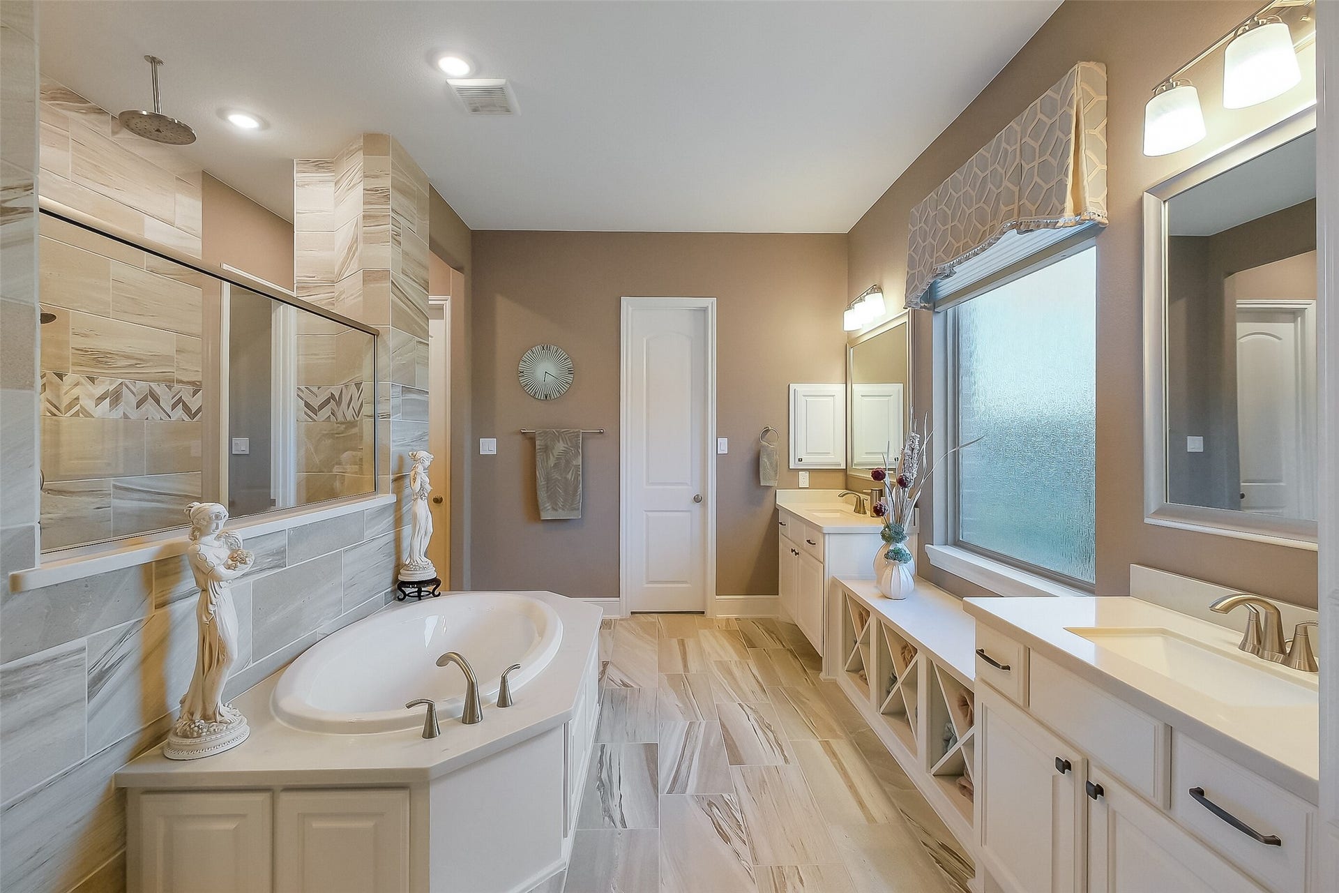 The primary bathroom is a true spa-style retreat, with a soaking tub, dual vanities, and a separate oversized walk-in shower. The window with privacy glass provides natural light and the pull-down blinds provide complete privacy if desired.