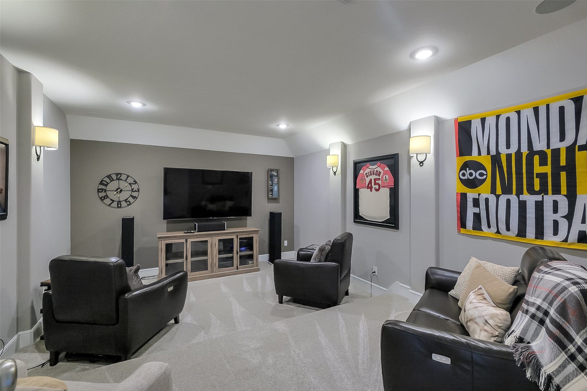 This media or game room is ready for movie marathons or big-game watch parties, with stadium seating with plush carpet, soft sconce lighting, and wired for surround sound.