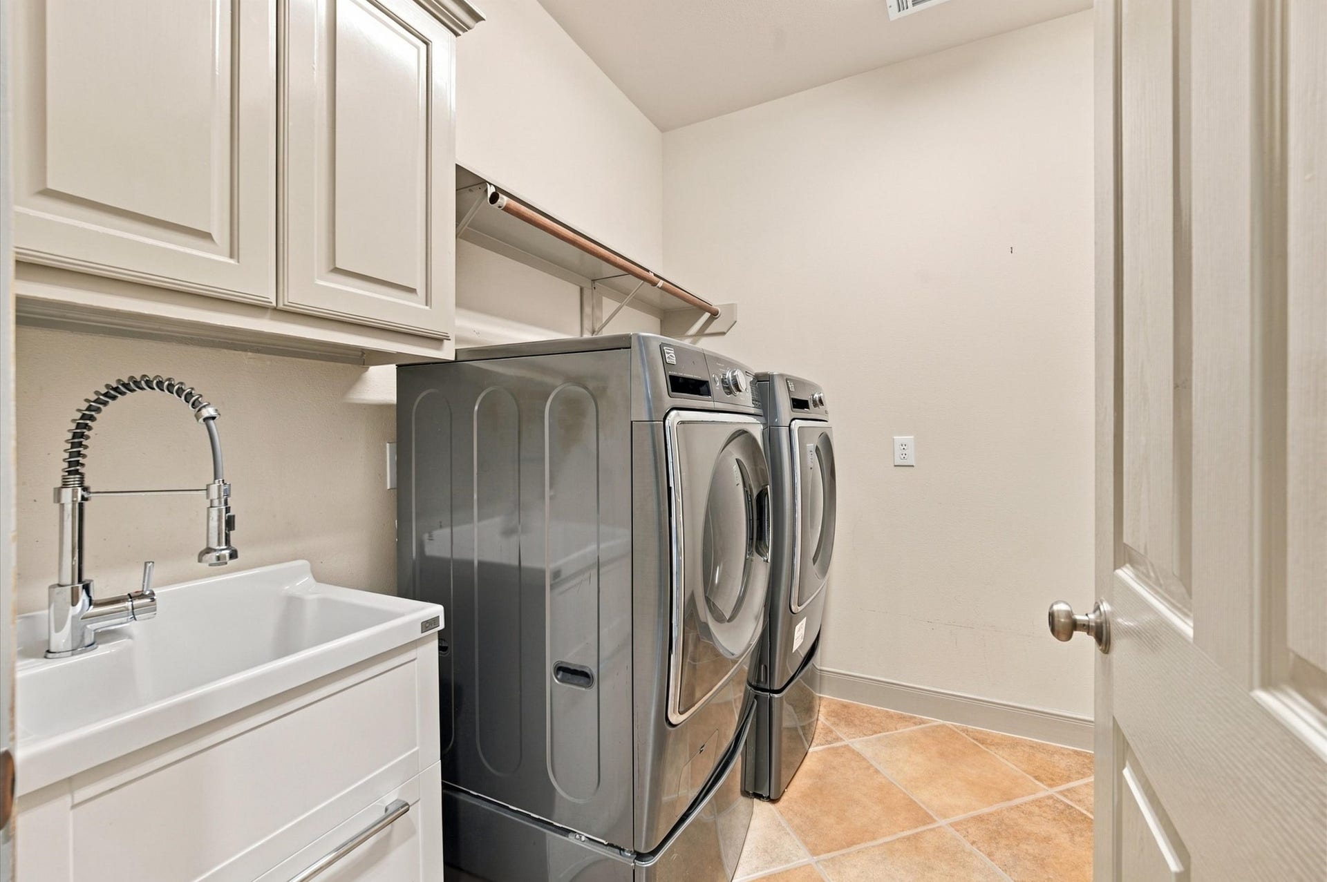 4427 Shady River, Missouri City, TX 77459 Modern laundry room featuring sleek stainless steel appliances, ample cabinetry for storage, and a convenient utility sink.