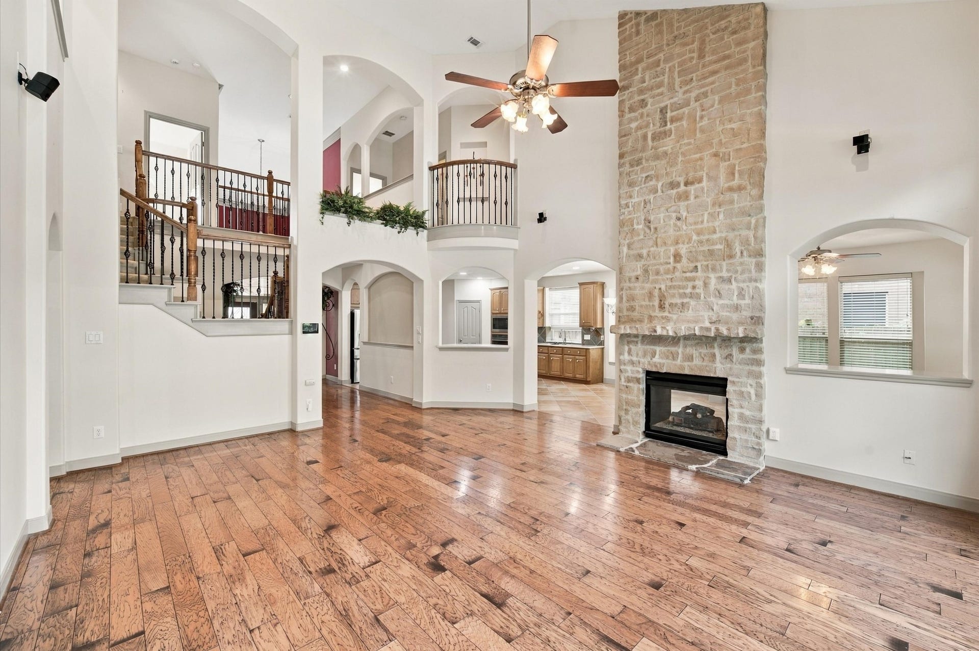 4427 Shady River, Missouri City, TX 77459 Stunning open-concept living space featuring a soaring stone fireplace, elegant hardwood floors, and a beautiful staircase with wrought iron railings.