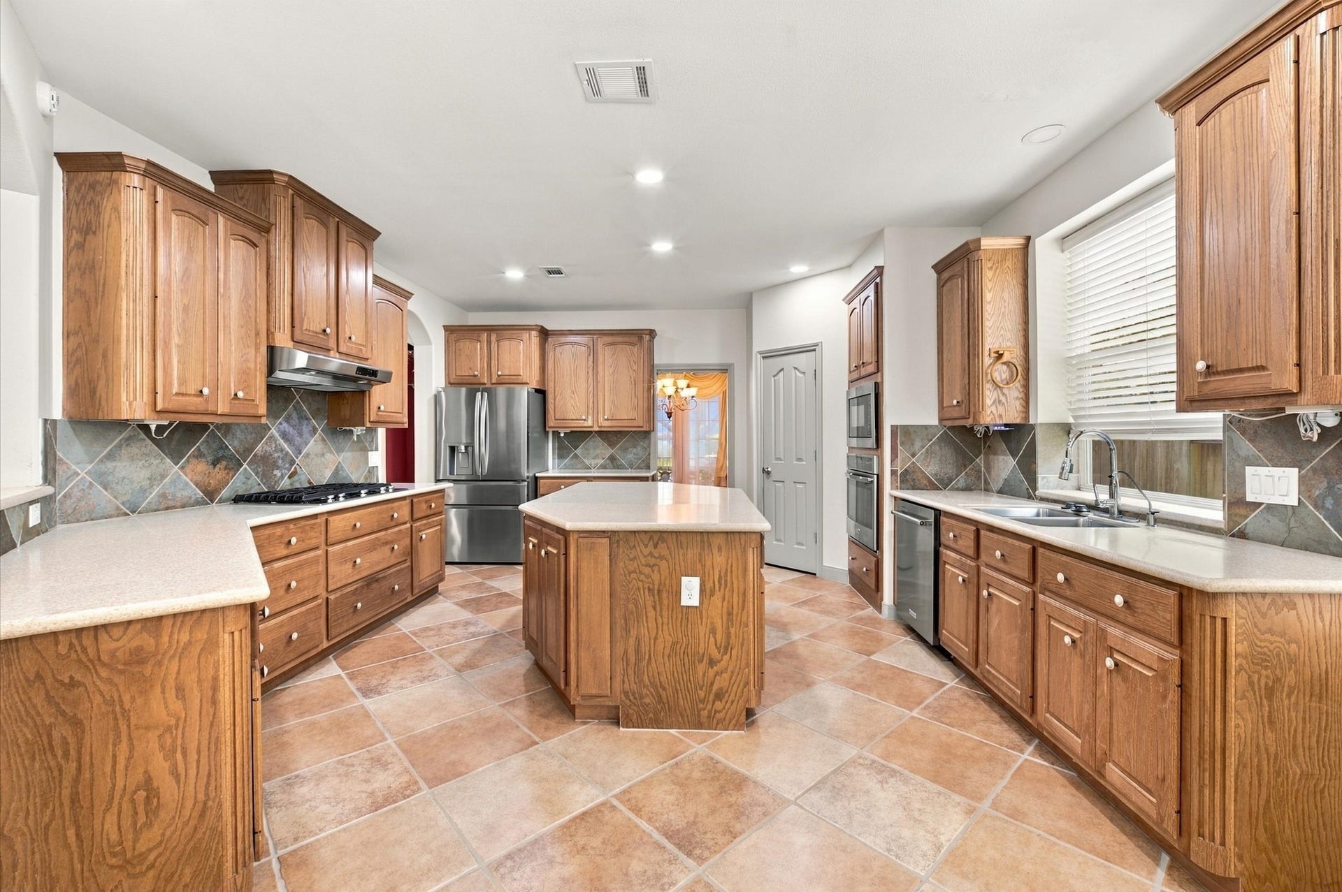 4427 Shady River, Missouri City, TX 77459 Spacious kitchen with rich wood cabinetry, sleek stainless steel appliances, and a central island, all complemented by elegant tile flooring and ample counter space.