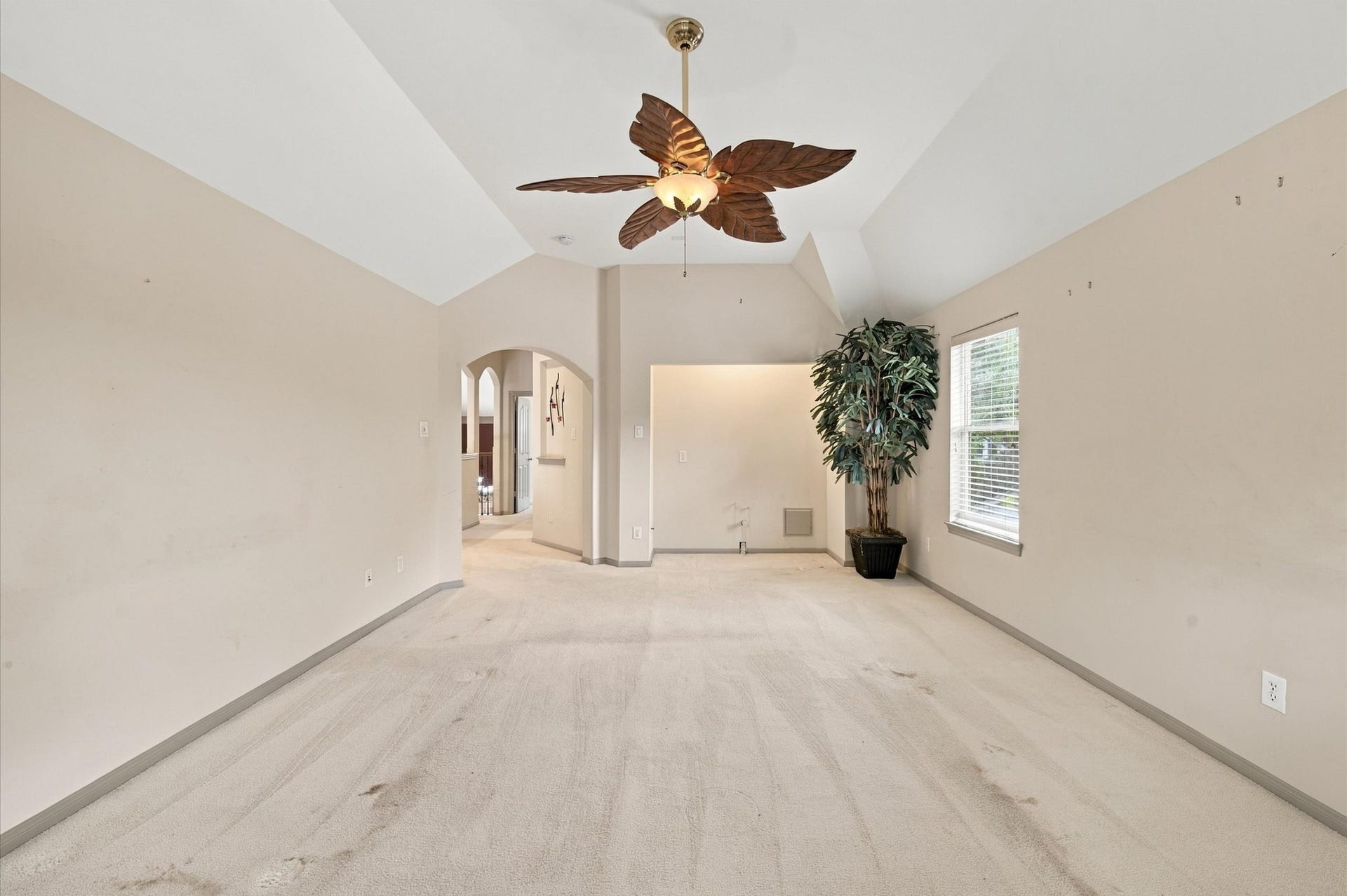 4427 Shady River, Missouri City, TX 77459 Spacious room featuring a high vaulted ceiling, elegant archway, and a charming ceiling fan with leaf-shaped blades, offering abundant natural light through a large window.