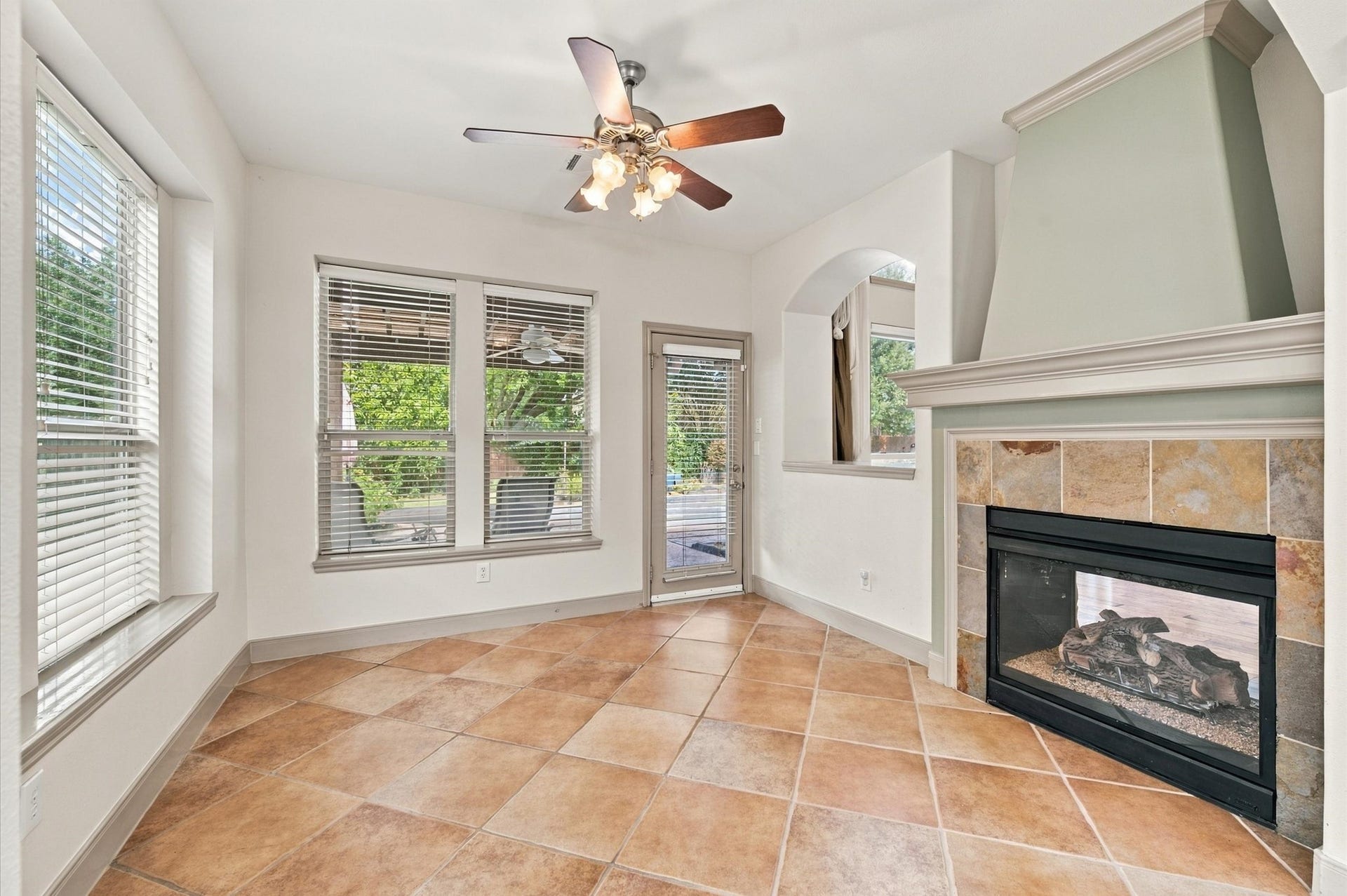 4427 Shady River, Missouri City, TX 77459 Cozy room with abundant natural light, featuring a charming corner fireplace and sleek tile flooring, perfect for relaxing or entertaining.