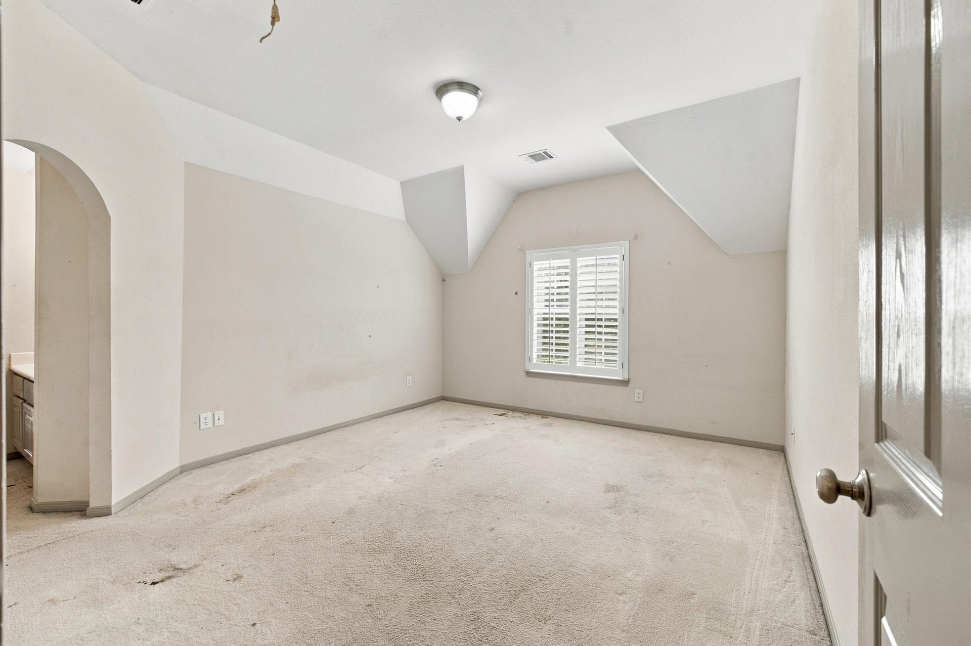 4427 Shady River, Missouri City, TX 77459 Bright room with unique angled ceiling details, featuring a window with shutters for natural light, and an inviting archway leading to an adjoining space.