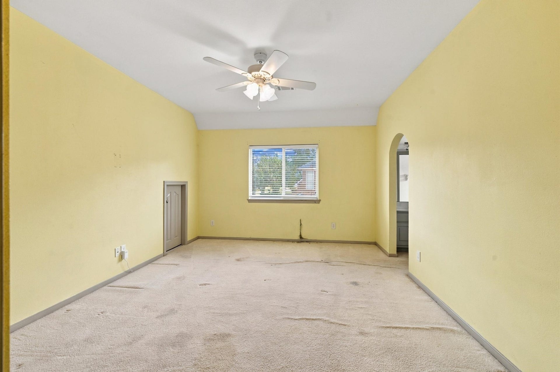 4427 Shady River, Missouri City, TX 77459 Spacious room with soft yellow walls, ceiling fan, and natural light from a central window, offering versatile use and charm.