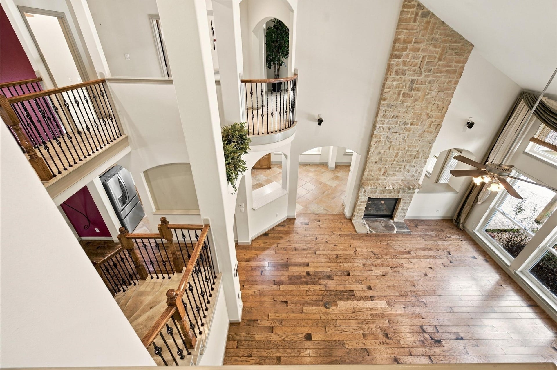4427 Shady River, Missouri City, TX 77459 Soaring ceilings and a stunning stone fireplace highlight this spacious living area, complemented by rich hardwood floors and abundant natural light from large windows.