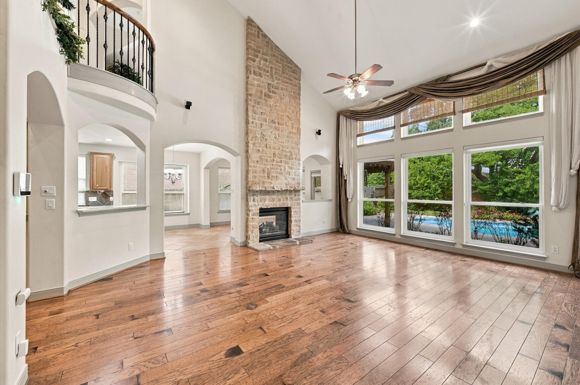 4427 Shady River, Missouri City, TX 77459 Stunning living area featuring a soaring ceiling, elegant stone fireplace, and expansive windows offering abundant natural light with views of the lush backyard and pool.