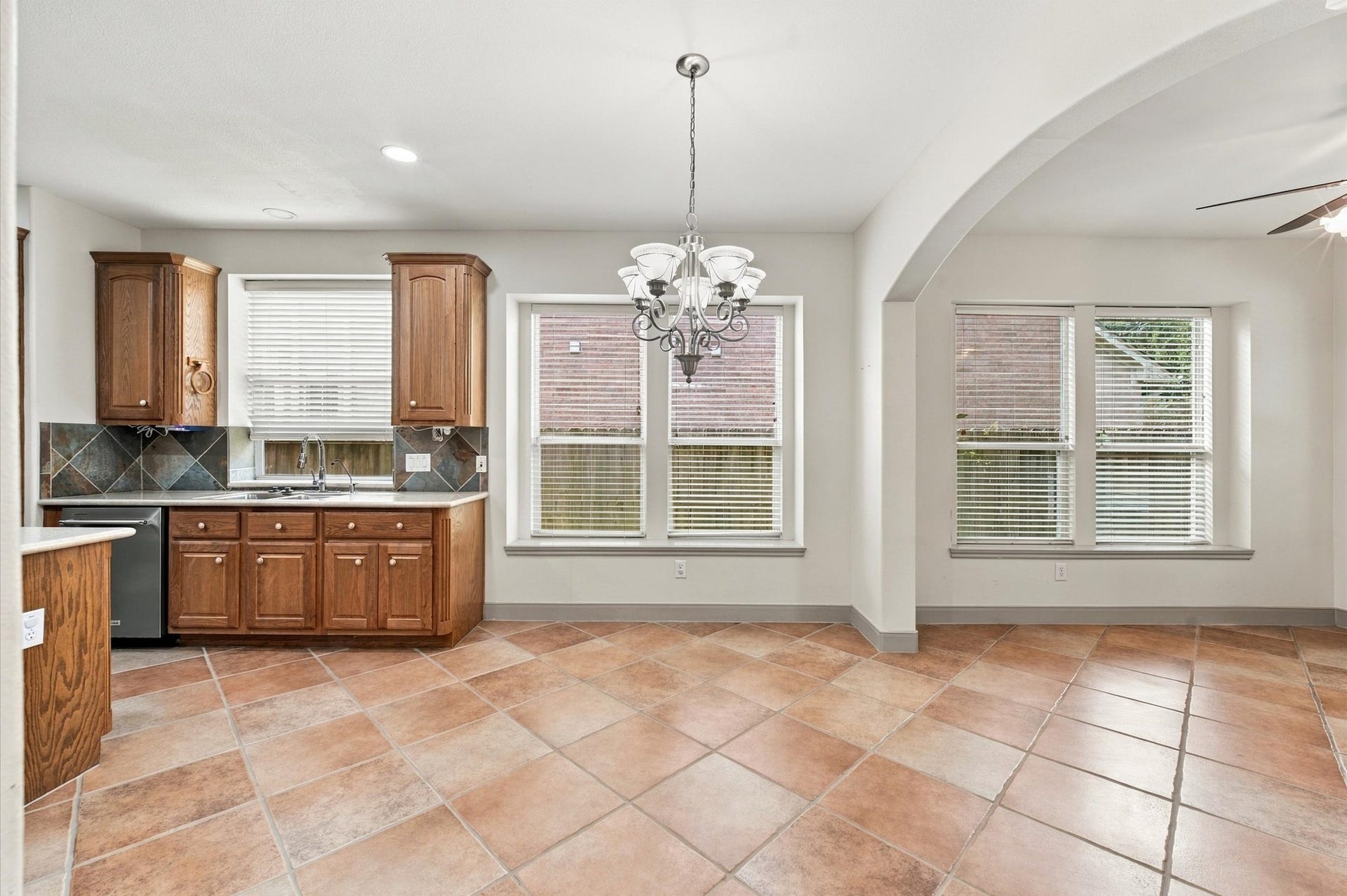 4427 Shady River, Missouri City, TX 77459 Bright kitchen area with classic wooden cabinetry, elegant tile flooring, and a charming chandelier, offering ample natural light and an inviting atmosphere.