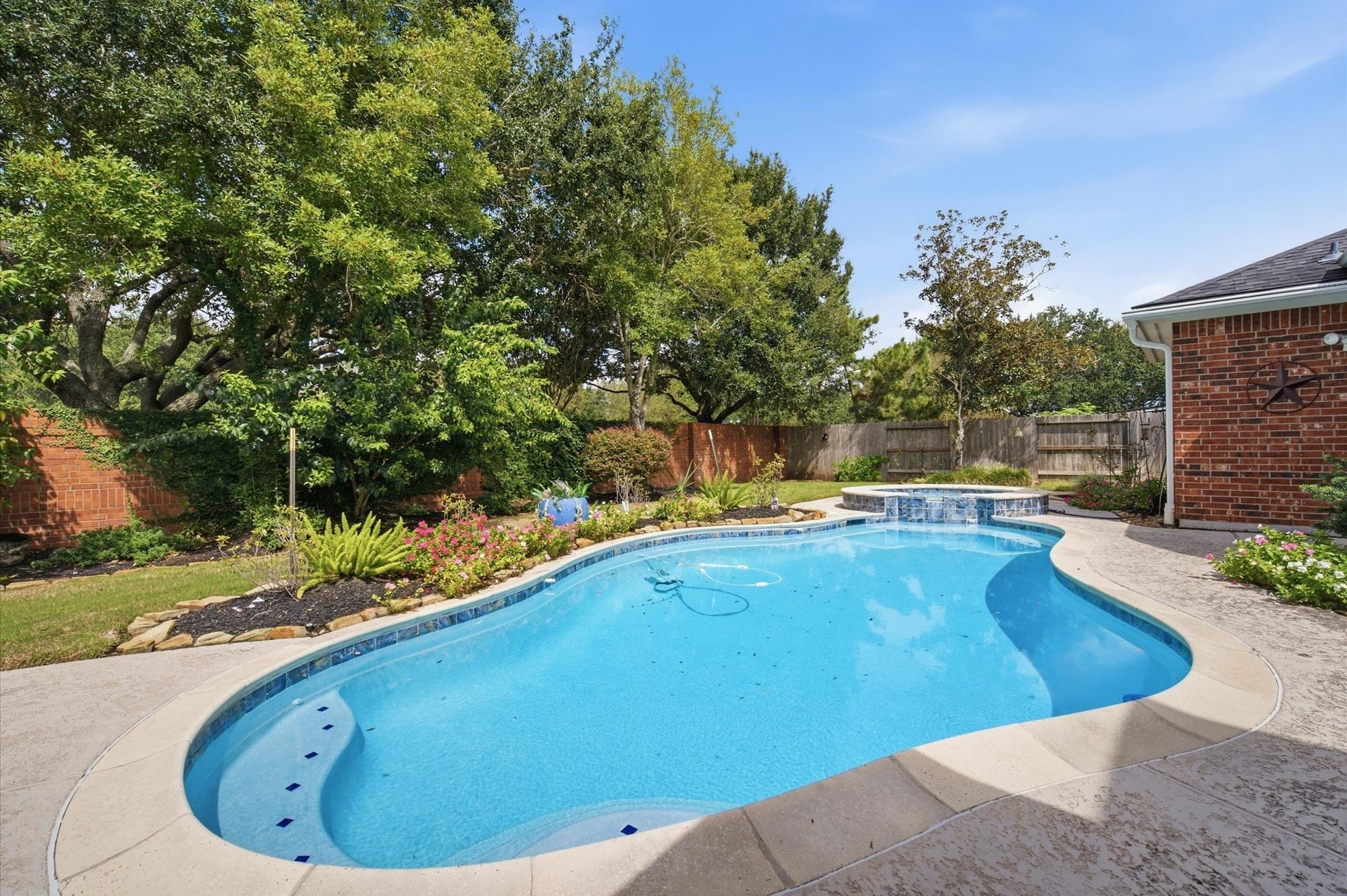 4427 Shady River, Missouri City, TX 77459 Enjoy a refreshing retreat in this beautifully landscaped backyard, featuring a sparkling pool with a tranquil waterfall, surrounded by lush greenery and a privacy fence.