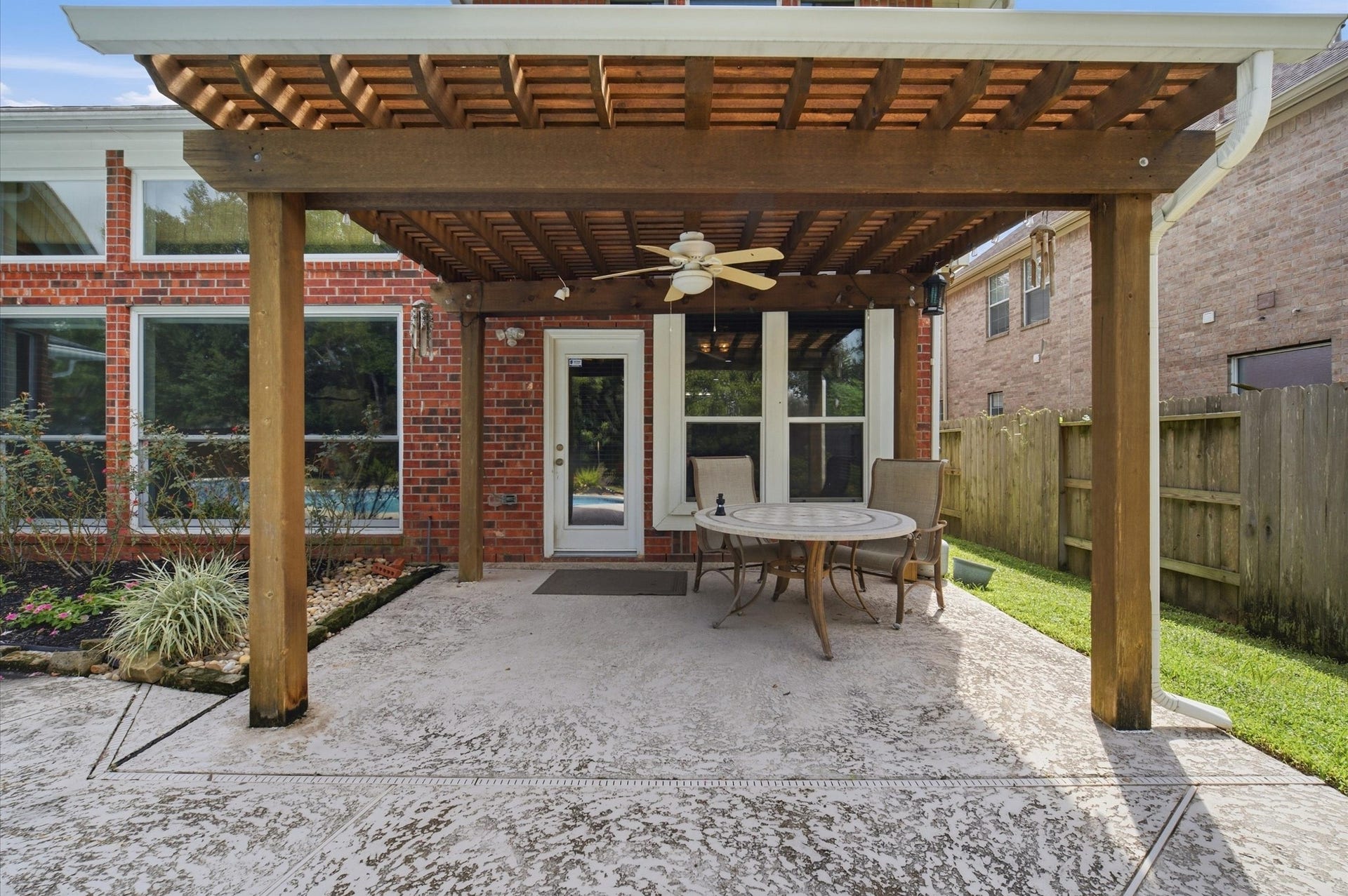 4427 Shady River, Missouri City, TX 77459 Charming backyard patio with a pergola, perfect for outdoor dining and relaxation, complemented by a ceiling fan and beautiful brick exterior.