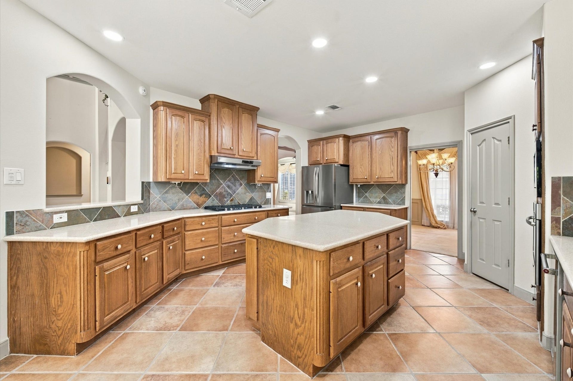 4427 Shady River, Missouri City, TX 77459 Spacious kitchen featuring warm wood cabinetry, a central island, and elegant tile flooring, perfect for entertaining and everyday cooking.