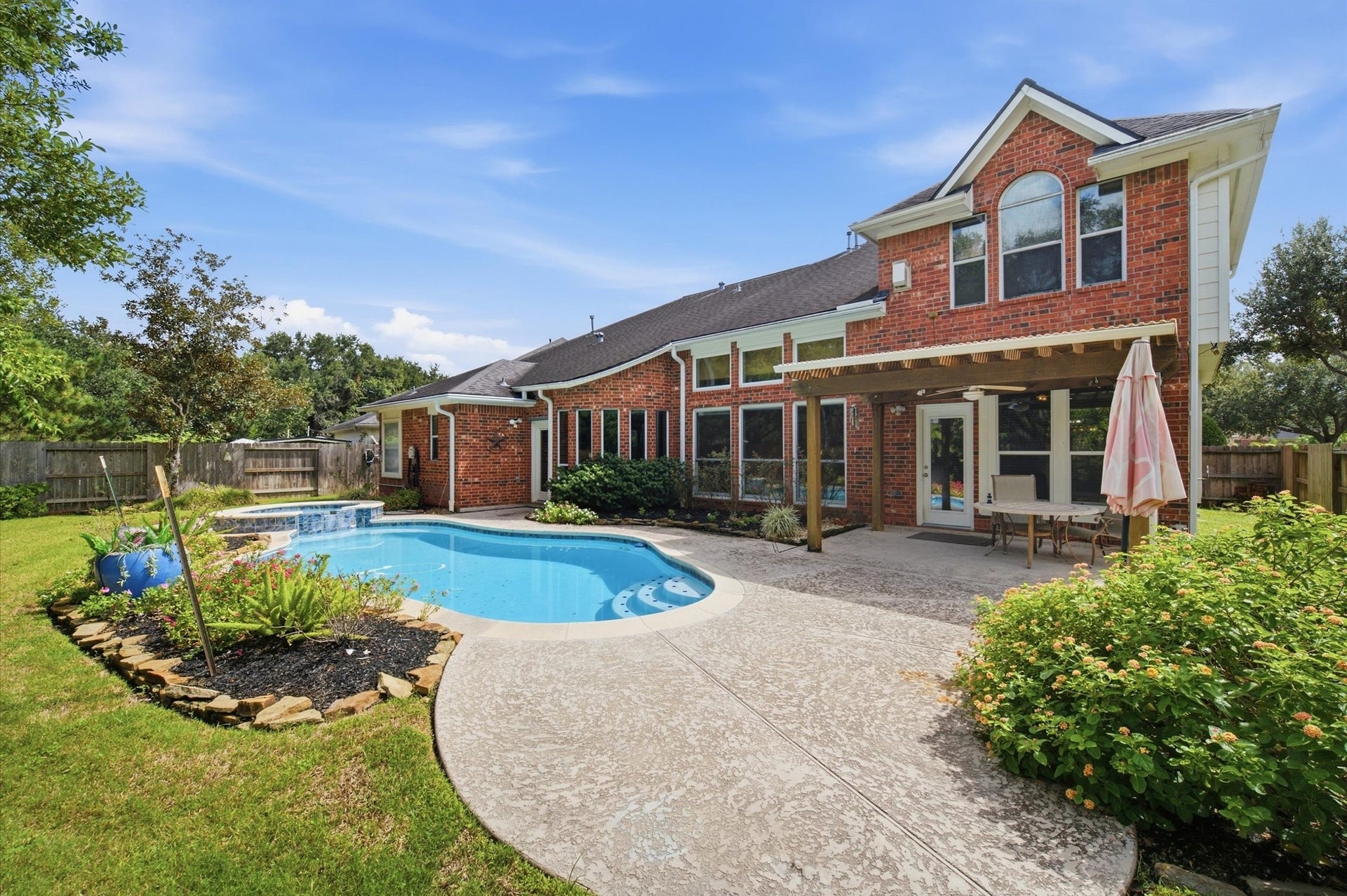 4427 Shady River, Missouri City, TX 77459 Charming two-story brick home with a spacious backyard featuring a sparkling pool, lush landscaping, and a cozy patio area perfect for outdoor entertaining.