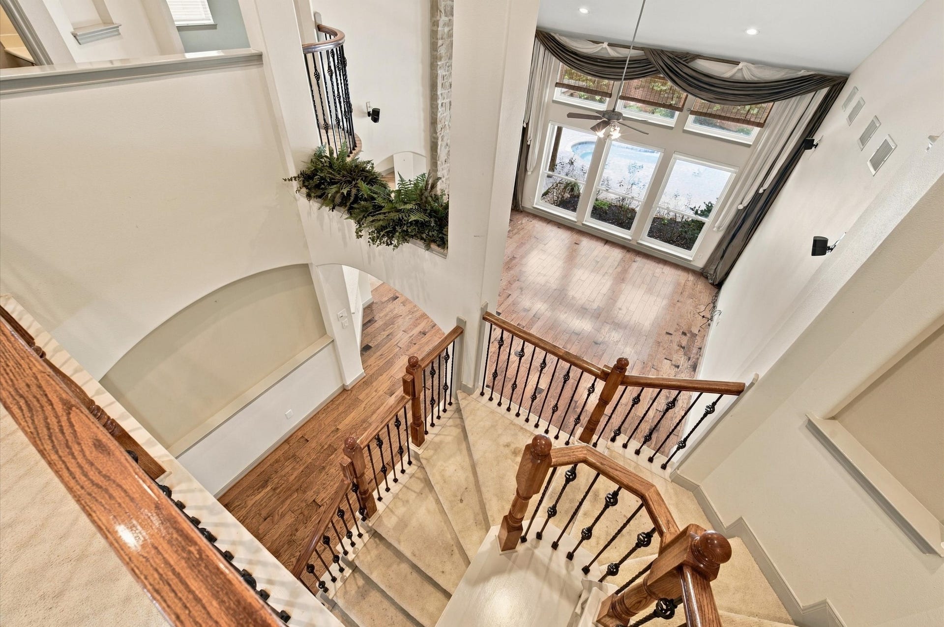 4427 Shady River, Missouri City, TX 77459 Elegant staircase with wooden railings leads to a bright, open living area featuring large windows and hardwood floors, offering a warm and inviting atmosphere.