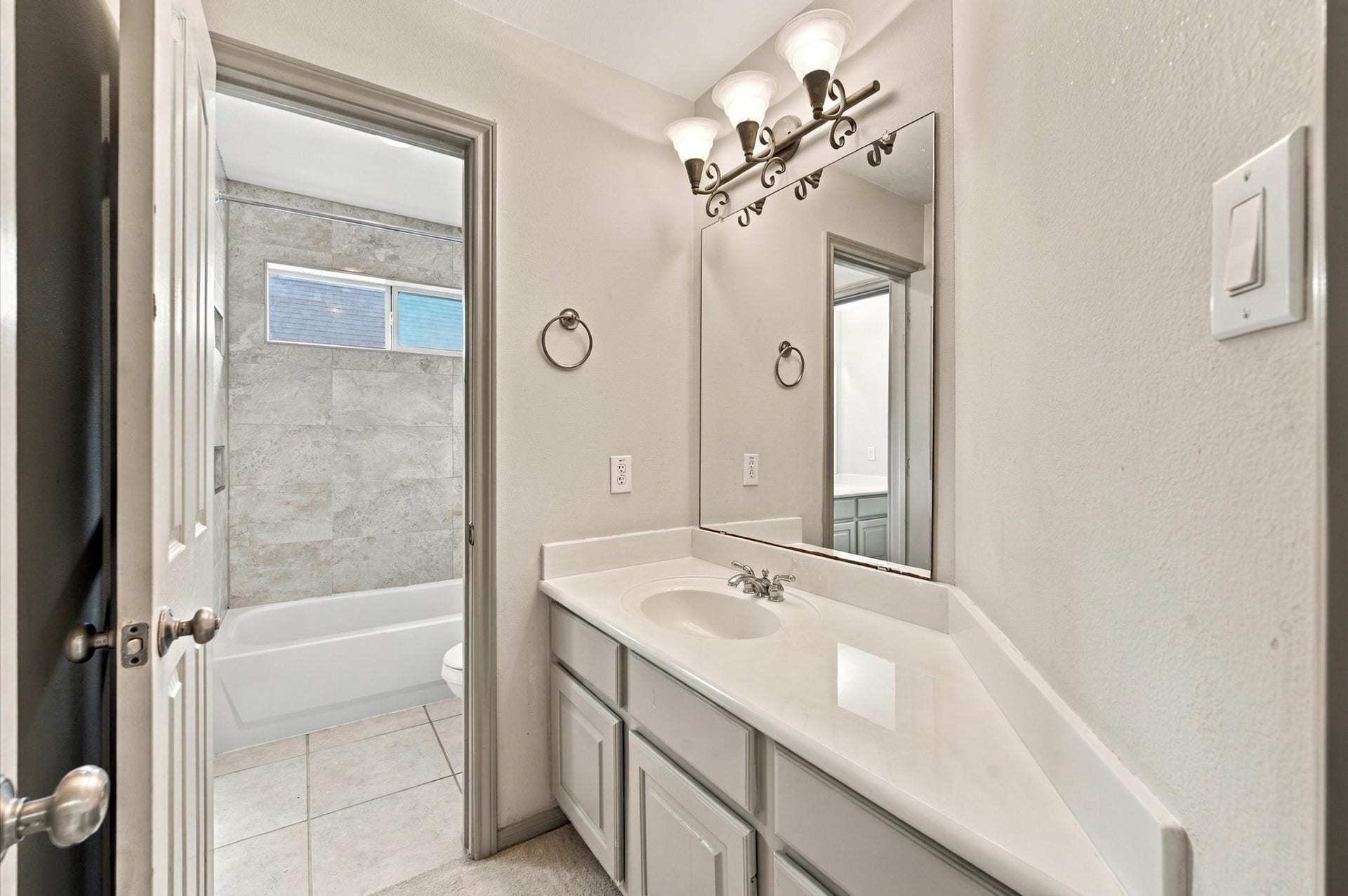 4427 Shady River, Missouri City, TX 77459 Bright bathroom featuring a spacious vanity with ample storage, elegant lighting, and a tiled shower-tub combination.