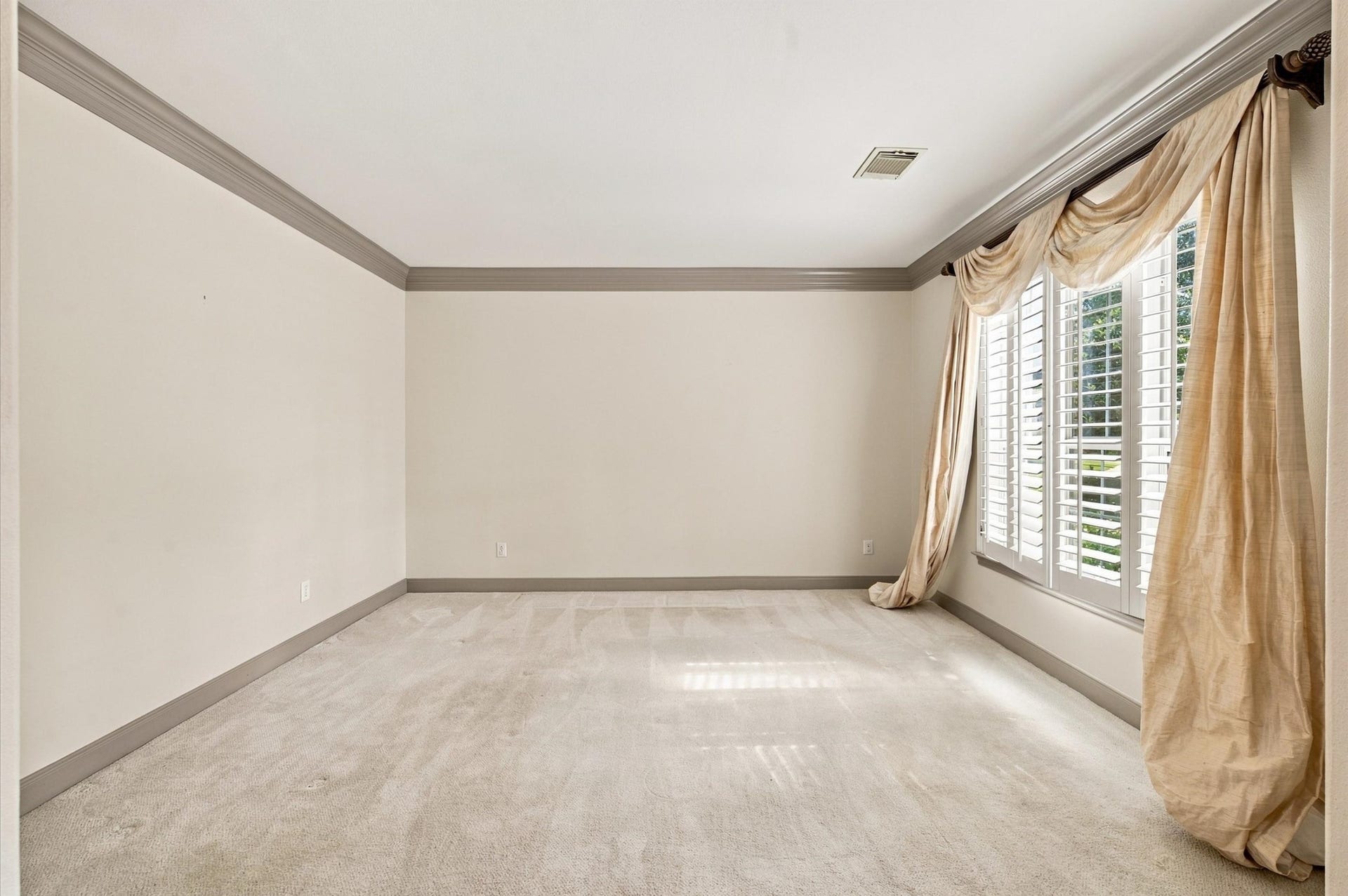 4427 Shady River, Missouri City, TX 77459 Spacious room with elegant crown molding, plush carpet, and large windows adorned with luxurious drapes, providing ample natural light.