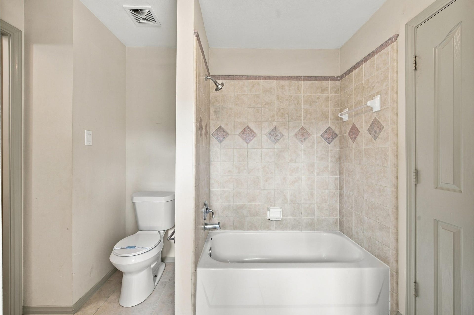 4427 Shady River, Missouri City, TX 77459 Charming bathroom featuring a tiled shower-tub combo with decorative accents and an adjacent toilet area, offering both functionality and style.