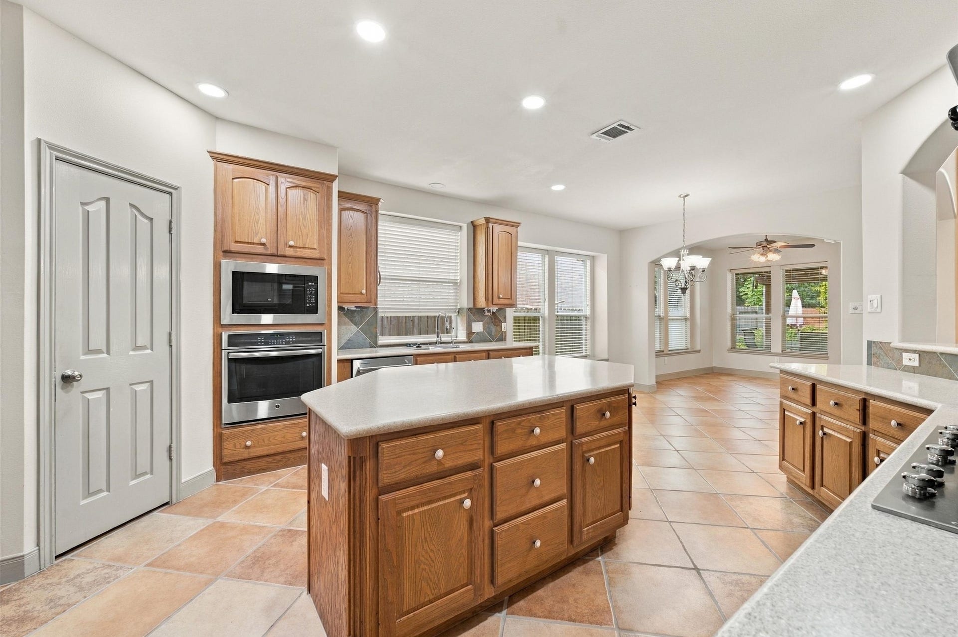 4427 Shady River, Missouri City, TX 77459 Spacious kitchen with elegant wood cabinetry, modern stainless steel appliances, and a large central island. The open layout flows seamlessly into a bright dining area with large windows, perfect for entertaining.