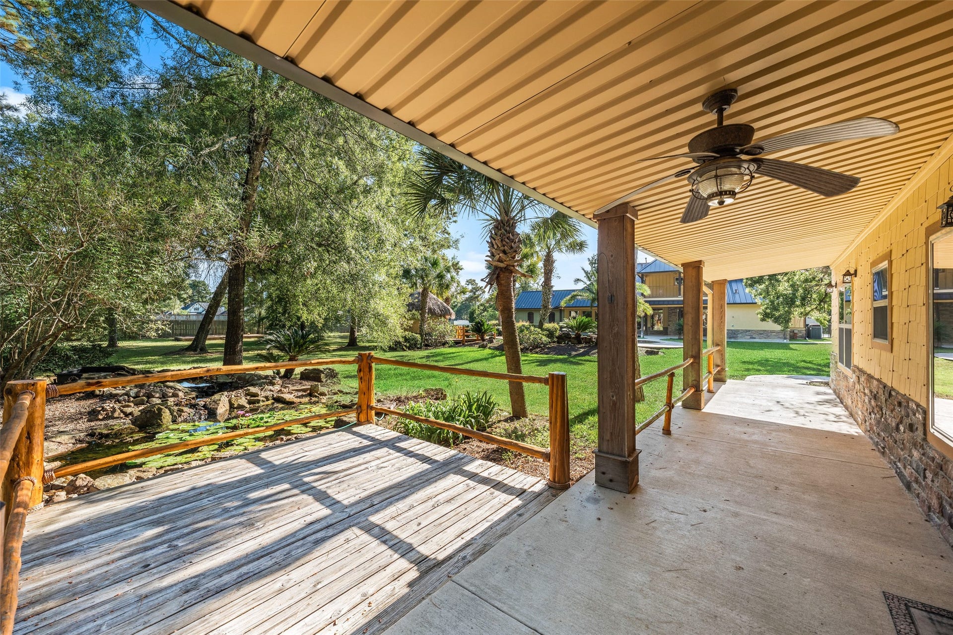 Charming covered porch off the guest house offers serene pond views and a cozy deck space.