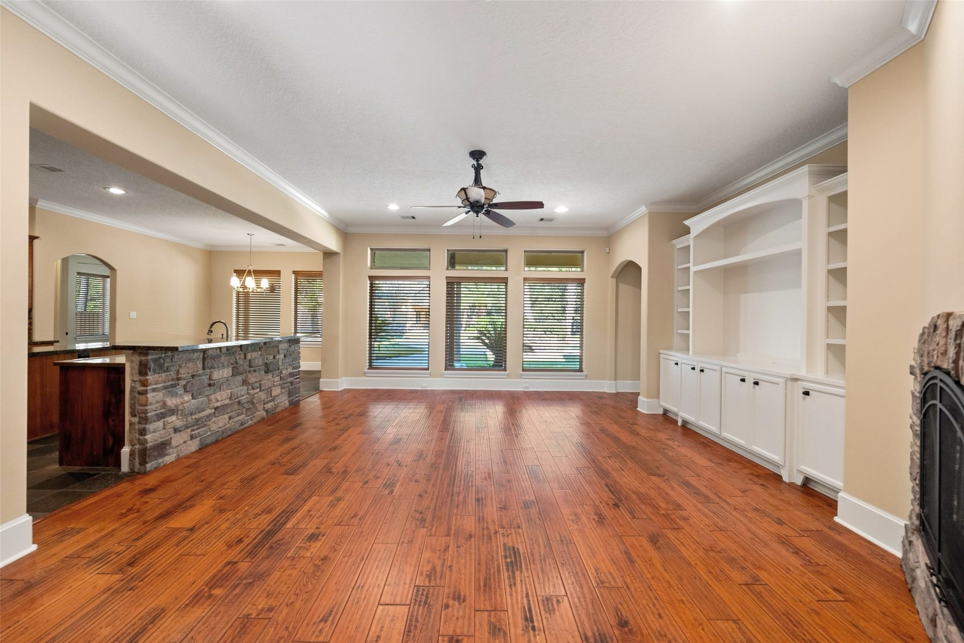 Spacious family room with large windows offering views of the private backyard, pool, and covered porch.