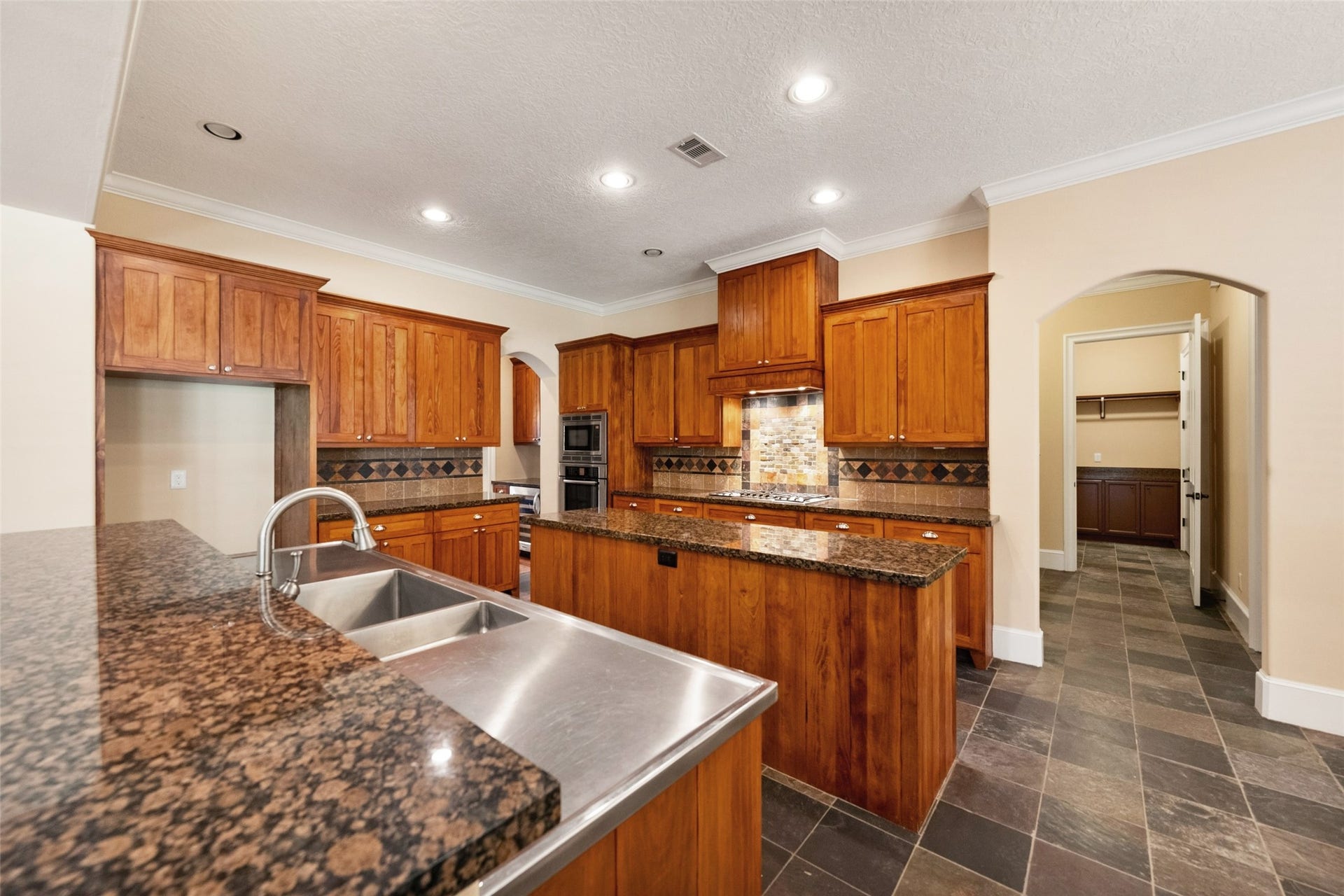 Luxurious kitchen featuring Bosch appliances, expansive granite countertops, a central island, and a butler's pantry with a wine fridge.