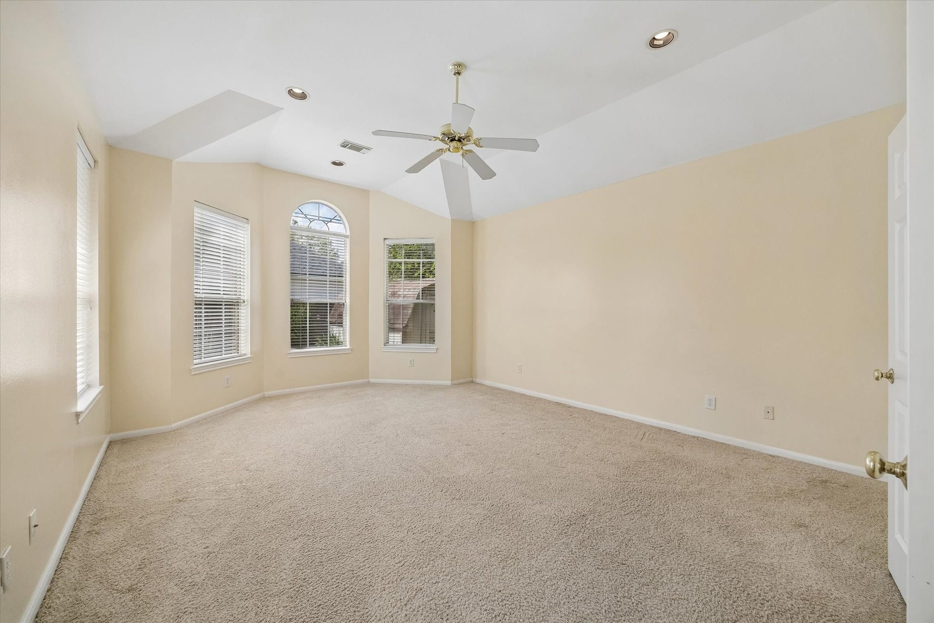 1115 Mulberry Lane, Bellaire, TX 77401 Spacious Primary Bedroom located on the first floor with vaulted ceilings, abundant natural light from large windows, and a ceiling fan for comfort.