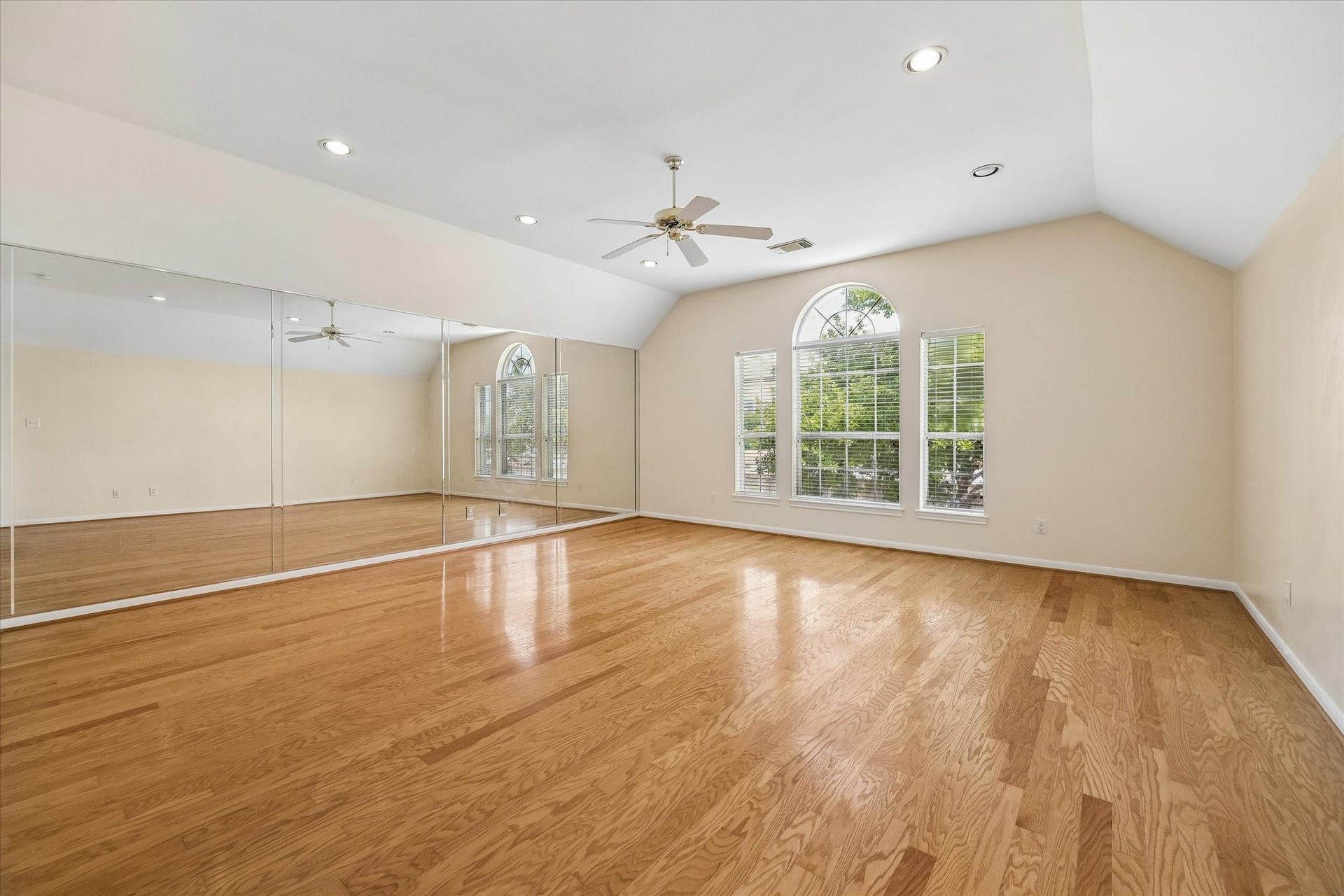 1115 Mulberry Lane, Bellaire, TX 77401 The gameroom with gleaming hardwood floors, large mirrored wall, vaulted ceiling, and abundant natural light from elegant arched windows is perfect for a pool table, workout room, or media room.