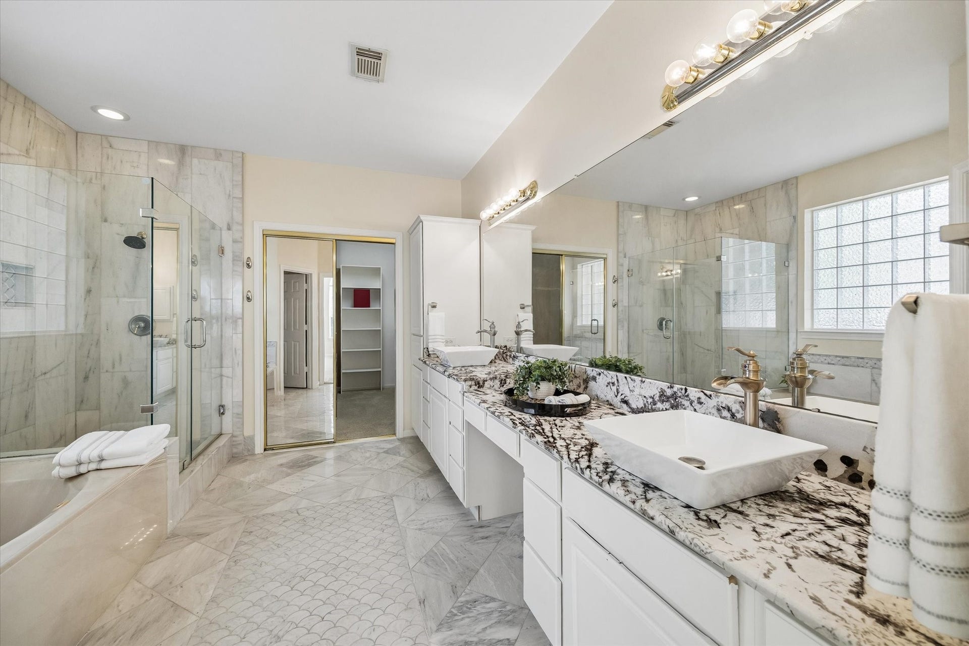 1115 Mulberry Lane, Bellaire, TX 77401 Spacious and elegant bathroom featuring dual sinks with granite countertops, a luxurious glass-enclosed shower, and a relaxing soaking tub with beautiful tile accents.